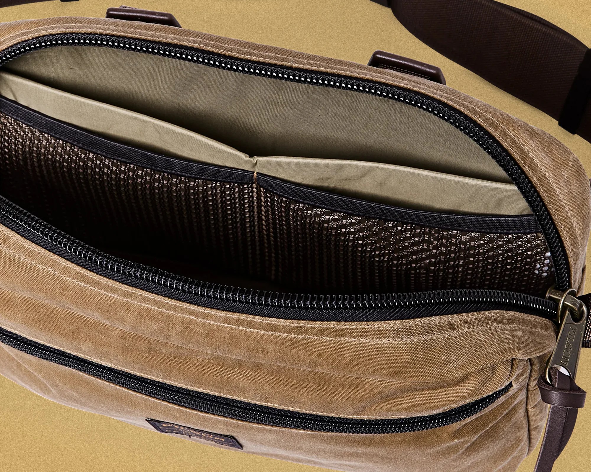 Brown canvas bag with black zipper and mesh pocket inside.