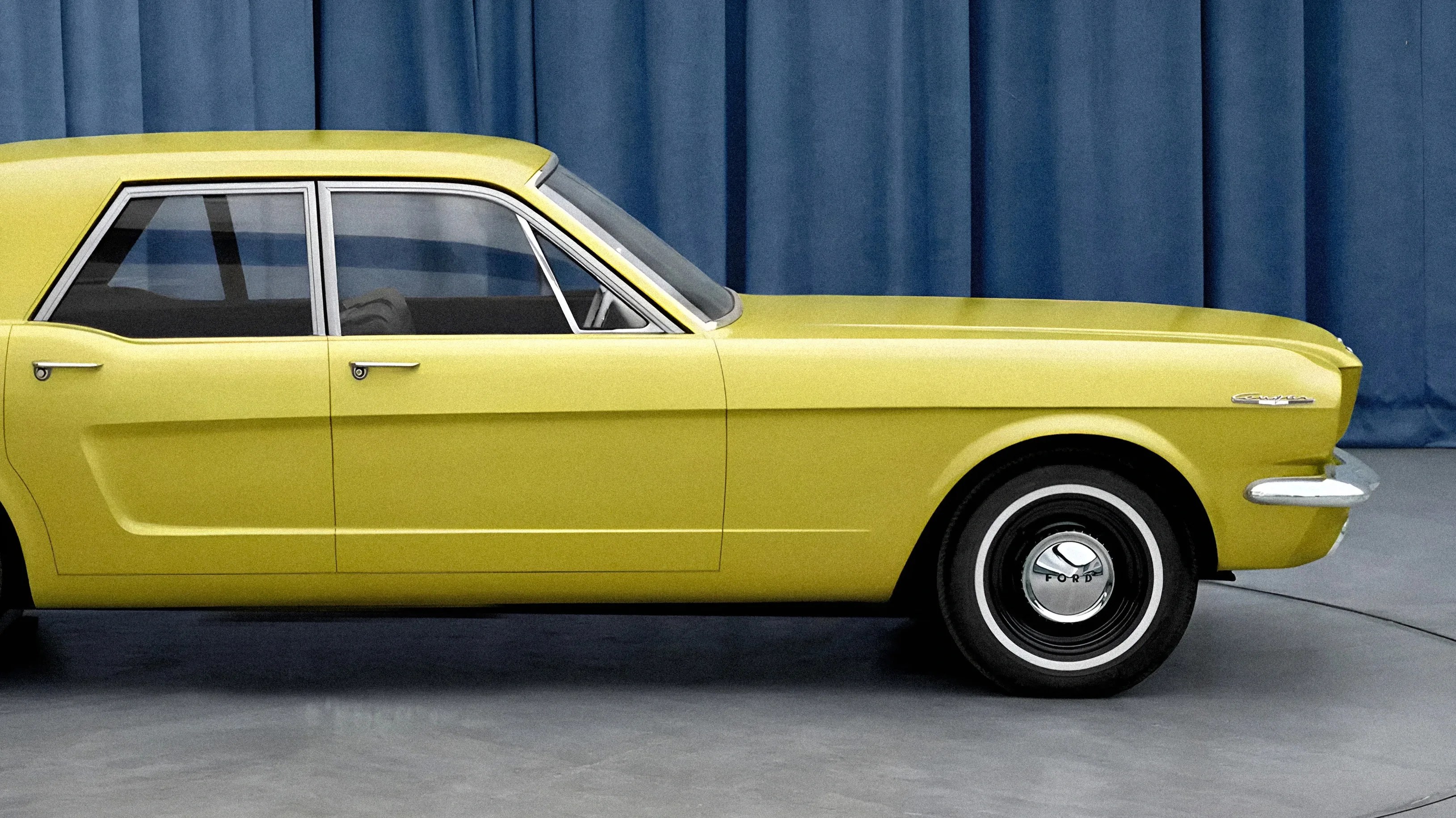 Yellow vintage Ford car side view with chrome trim and black tires with whitewall stripes.