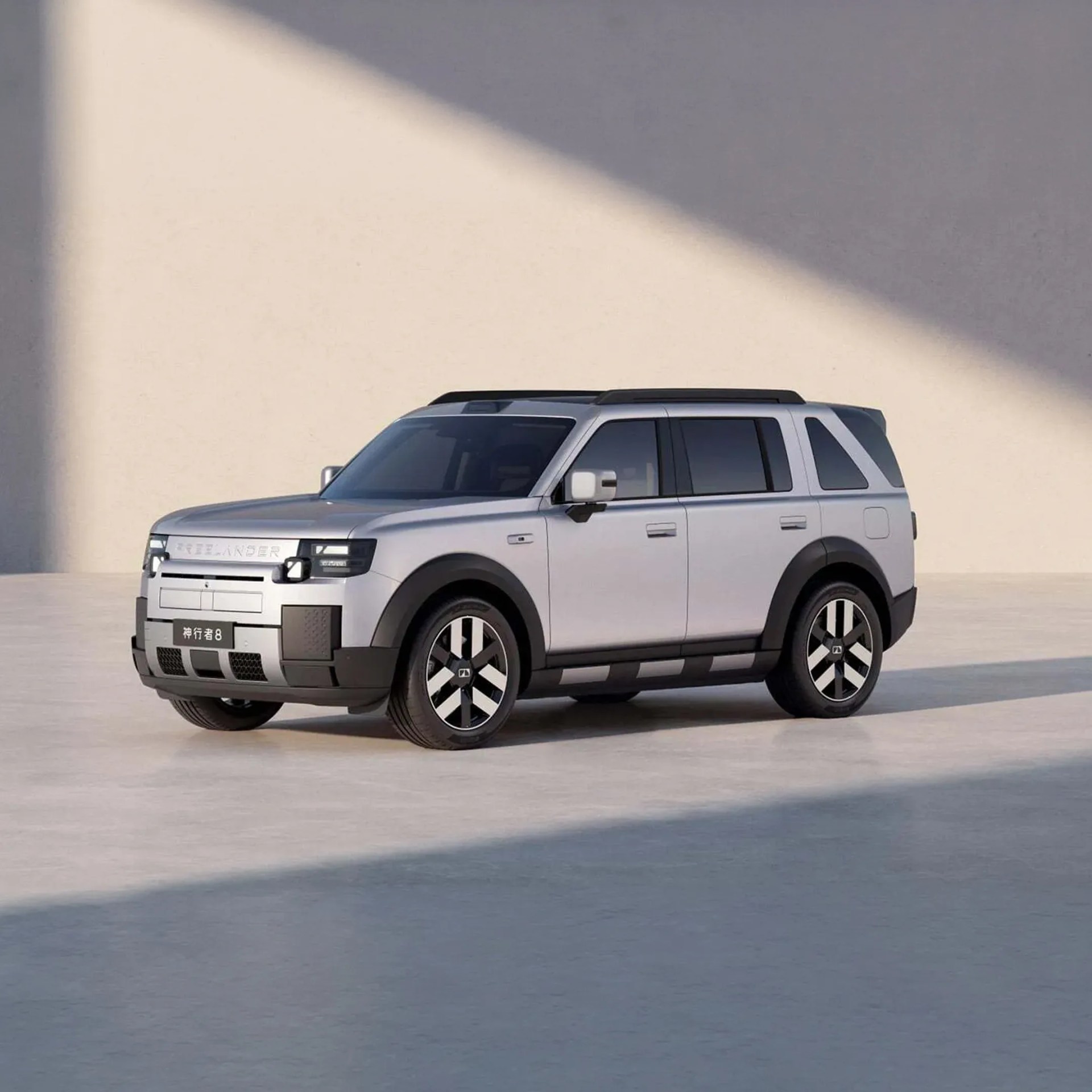 Silver electric SUV with black trim and distinctive geometric wheels parked on a light concrete surface.