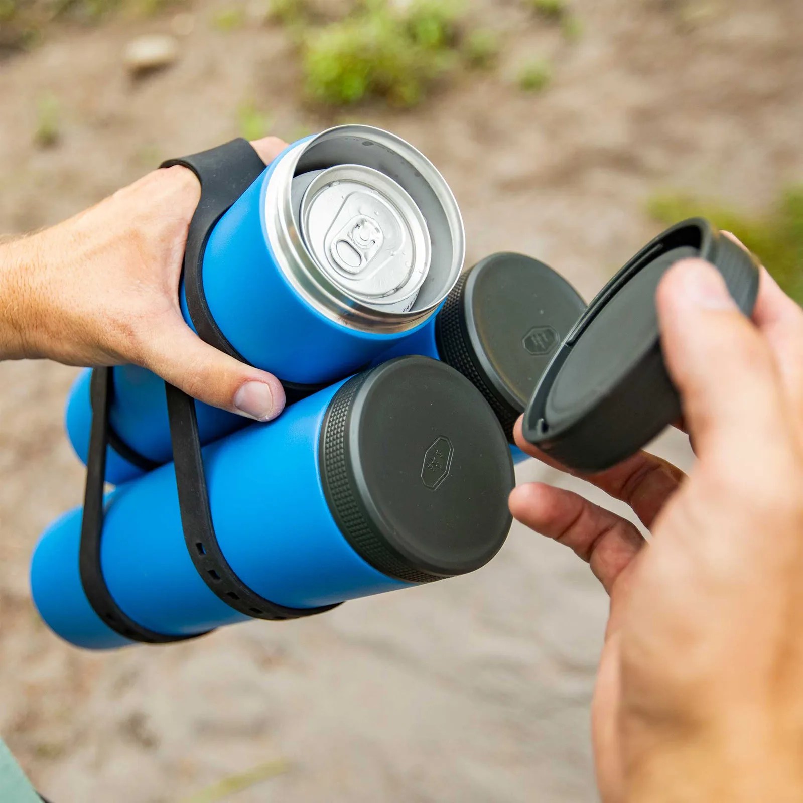 Blue insulated can cooler holding a silver soda can with black lids and a carrying strap.