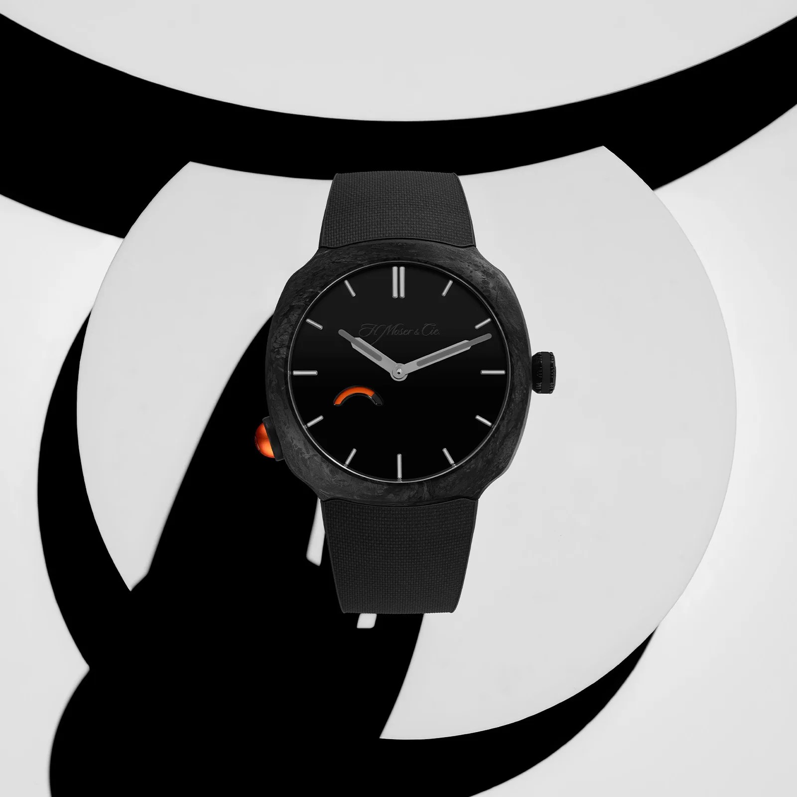 Black wristwatch with a textured black strap and orange accent on the left side, displayed on a black and white abstract background.
