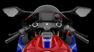 Close-up of a red and blue Honda Racing motorcycle dashboard with black handlebars, mirrors, and digital display.