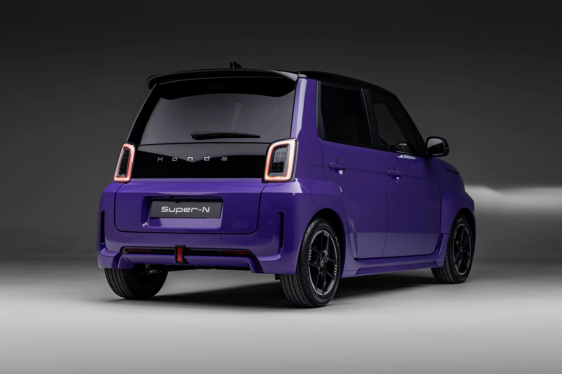 Purple Honda Super-N compact car with black roof and rear lights illuminated, shown from rear side.
