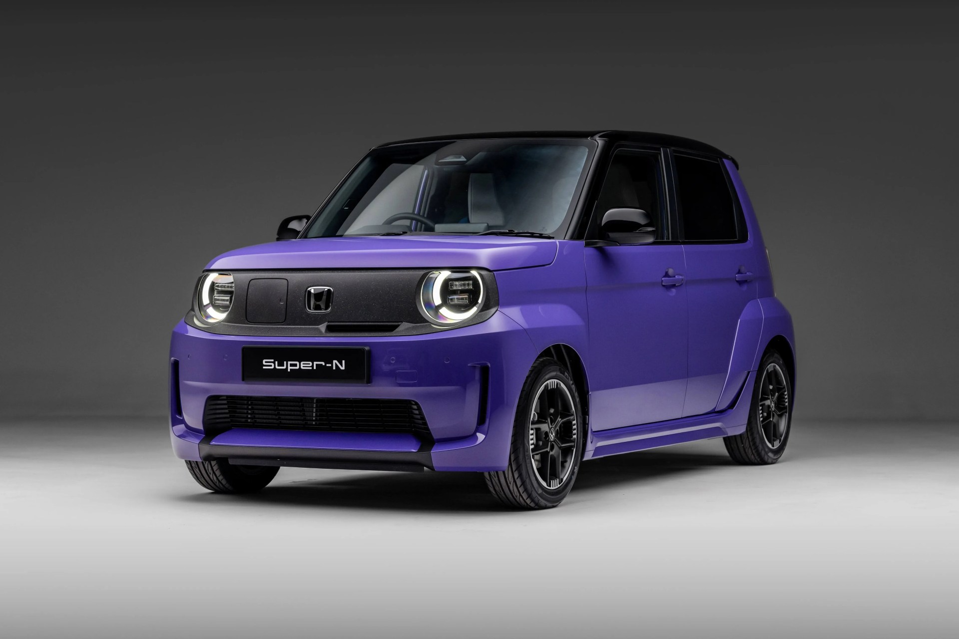 Compact purple Honda Super-N car with black roof and circular LED headlights on a gray studio floor.