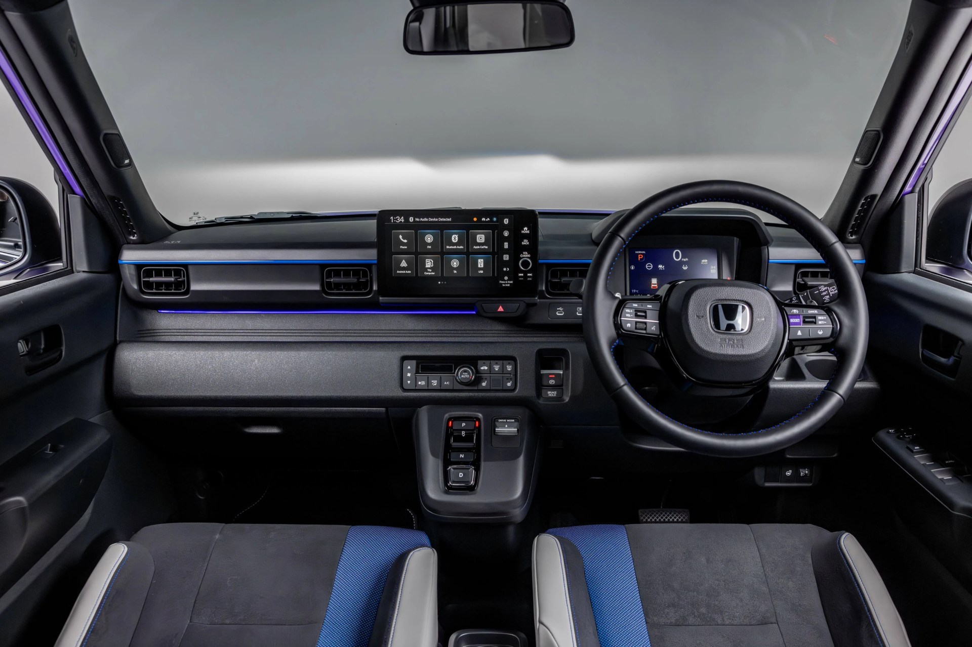 Minimalist car interior with black and blue fabric seats, digital dashboard, touchscreen infotainment, and push-button gear selector.