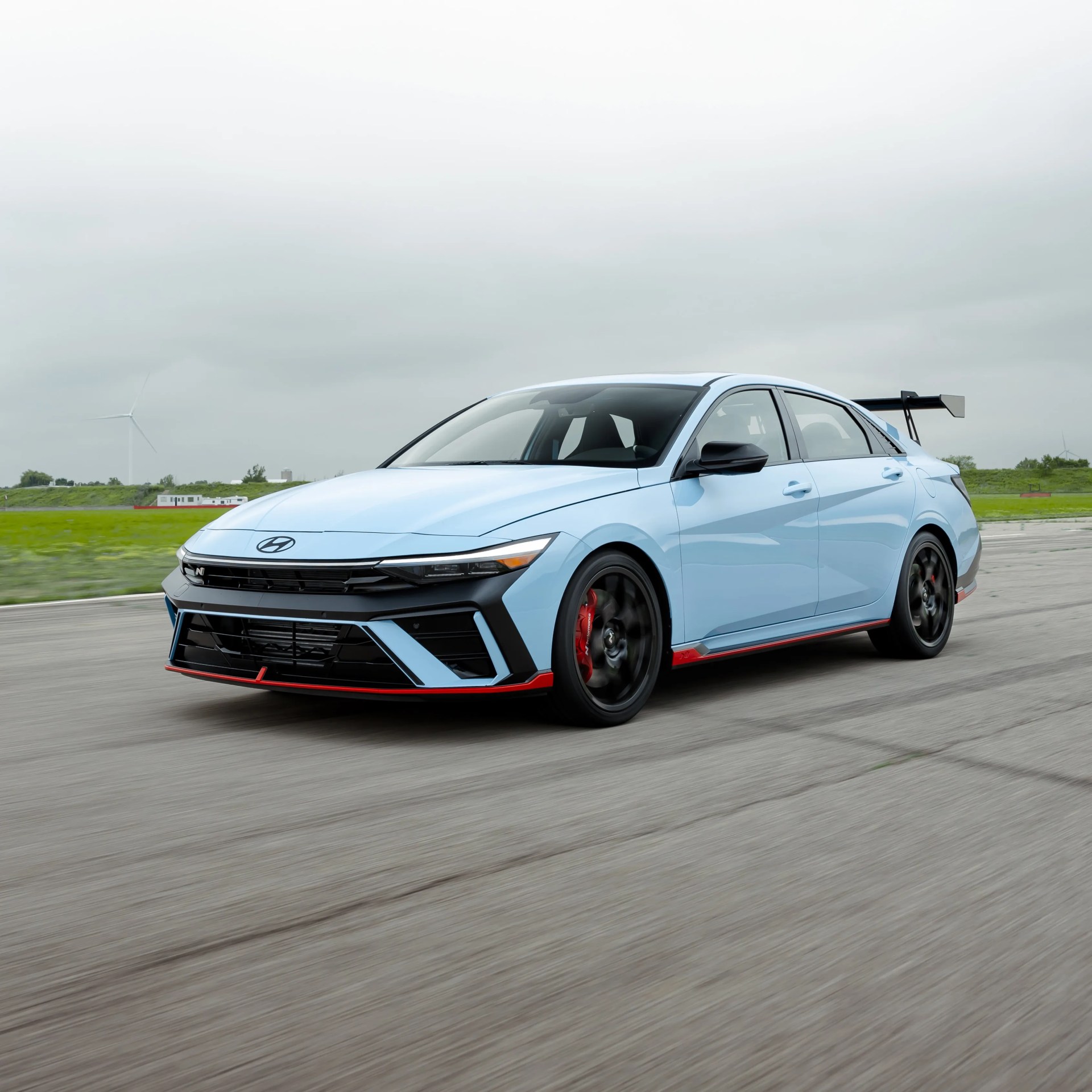 Light blue Hyundai sedan with black and red accents and a large rear spoiler on a racetrack.