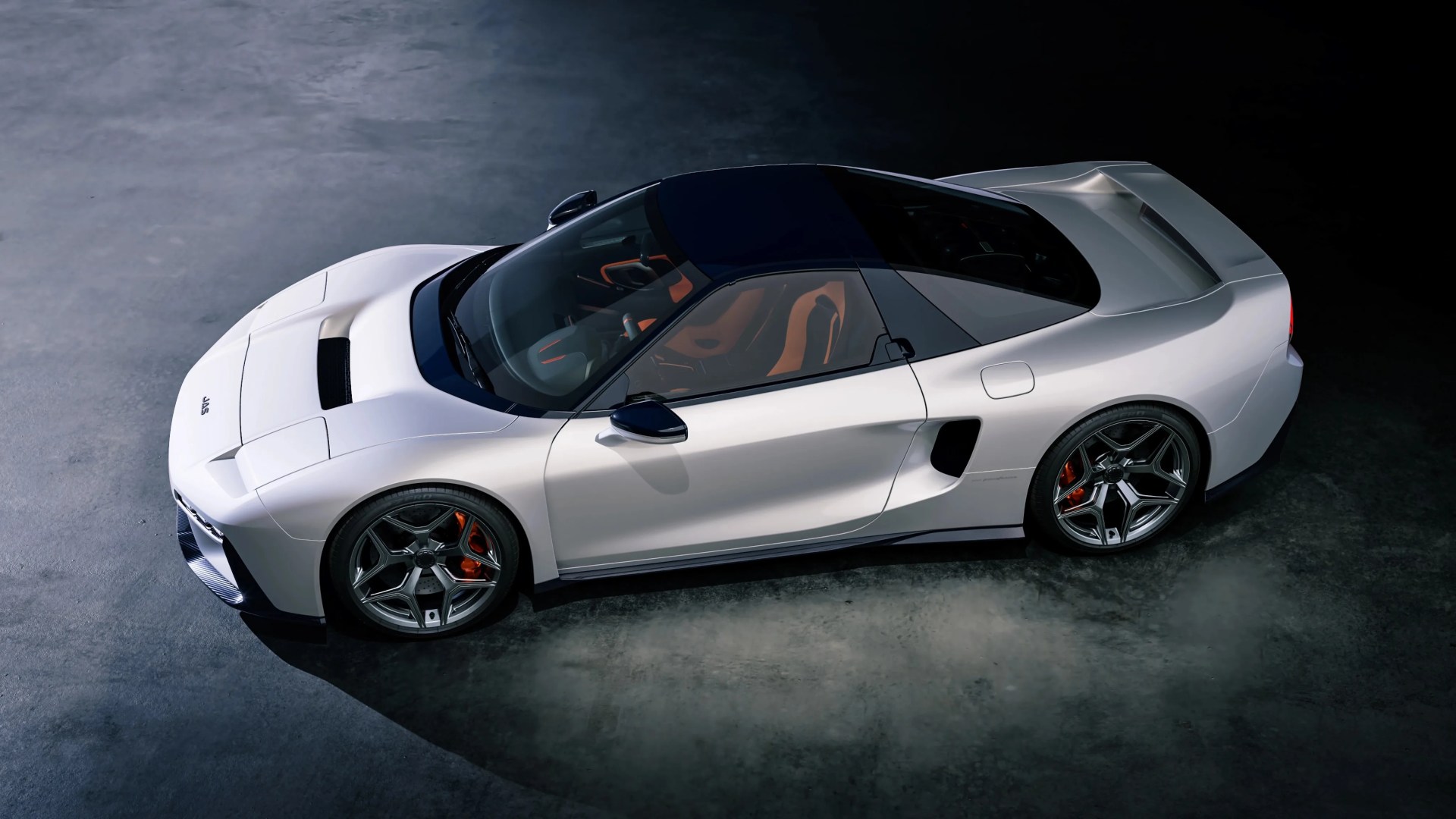 White sports car with black roof and orange interior, shown from a high side angle on a dark concrete floor.
