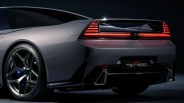 Rear view of a gray JAS Tensei sports car with illuminated horizontal taillights and black alloy wheels.