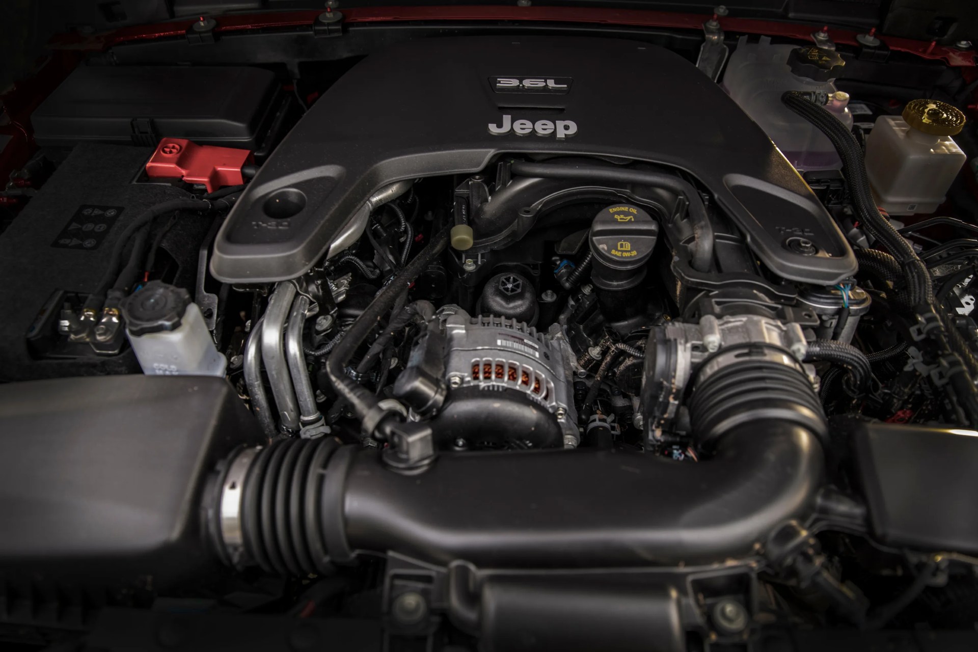 3.6L Jeep engine with black plastic cover and visible alternator and air intake components.