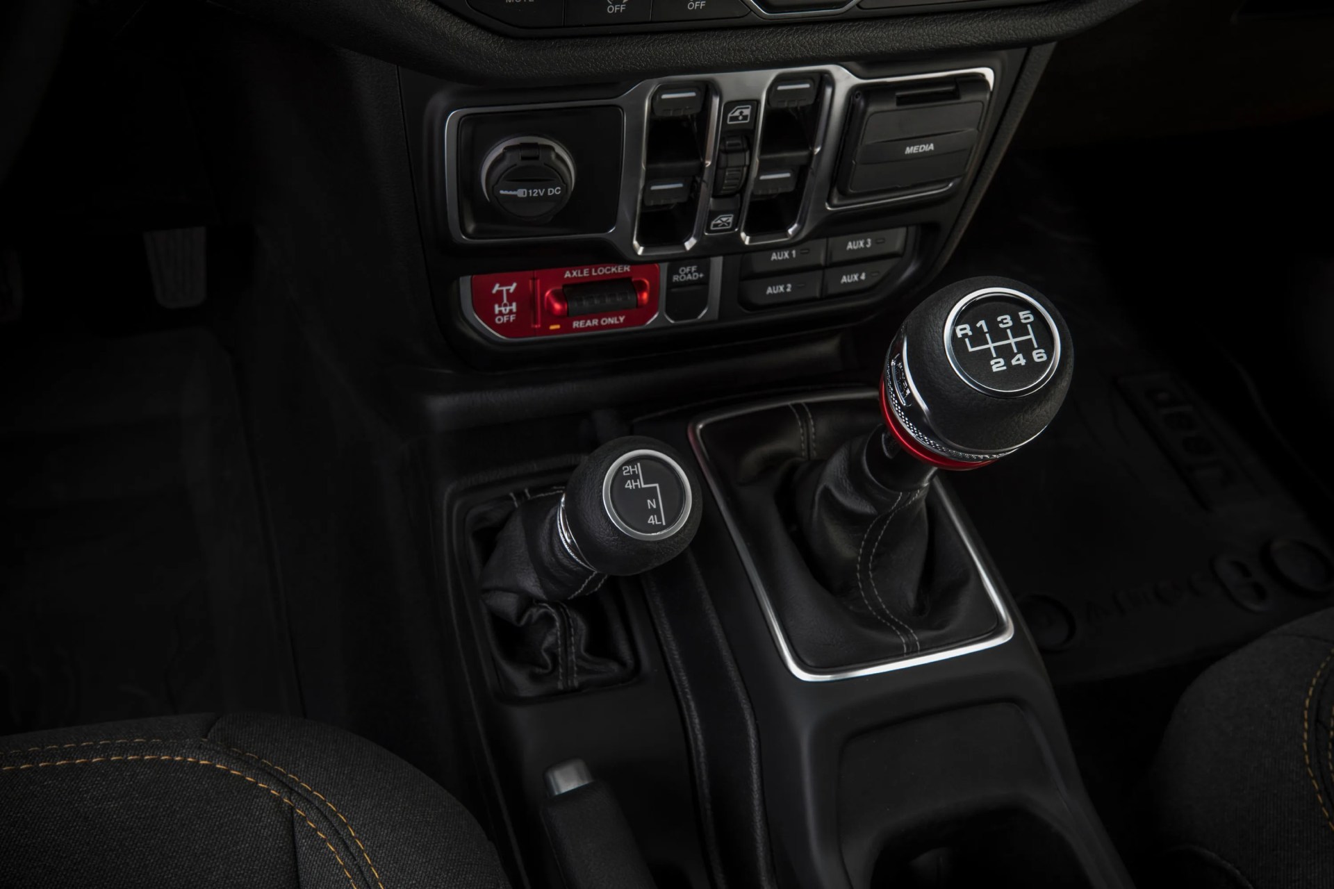 Black manual gear shift and 4WD selector levers with white markings in a vehicle center console.