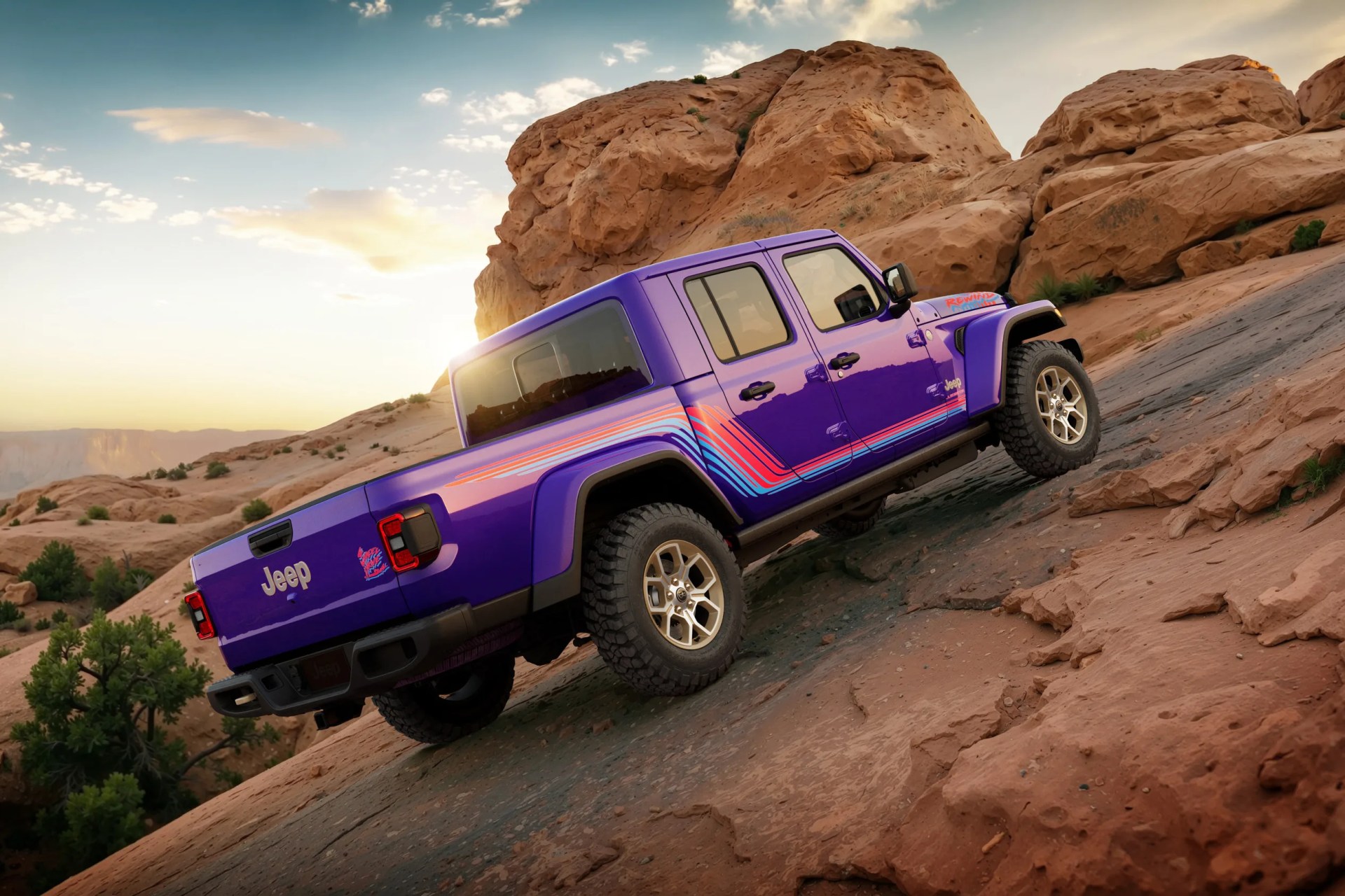 Purple Jeep pickup truck with red and blue stripes climbing rocky terrain at sunset.