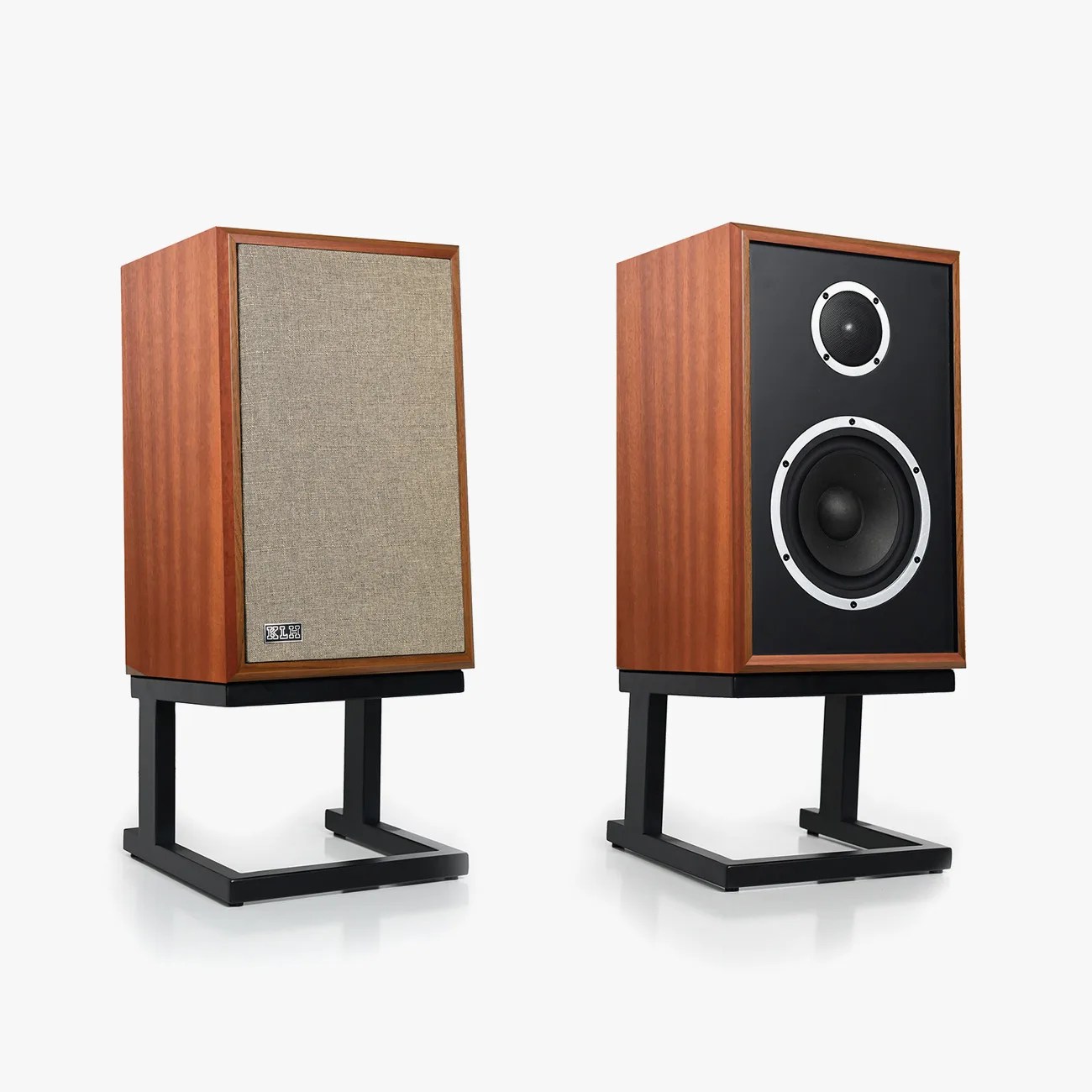 Pair of vintage-style bookshelf speakers with wooden cabinets, one with a beige fabric grille and the other showing black front with silver-ringed drivers, on black metal stands.