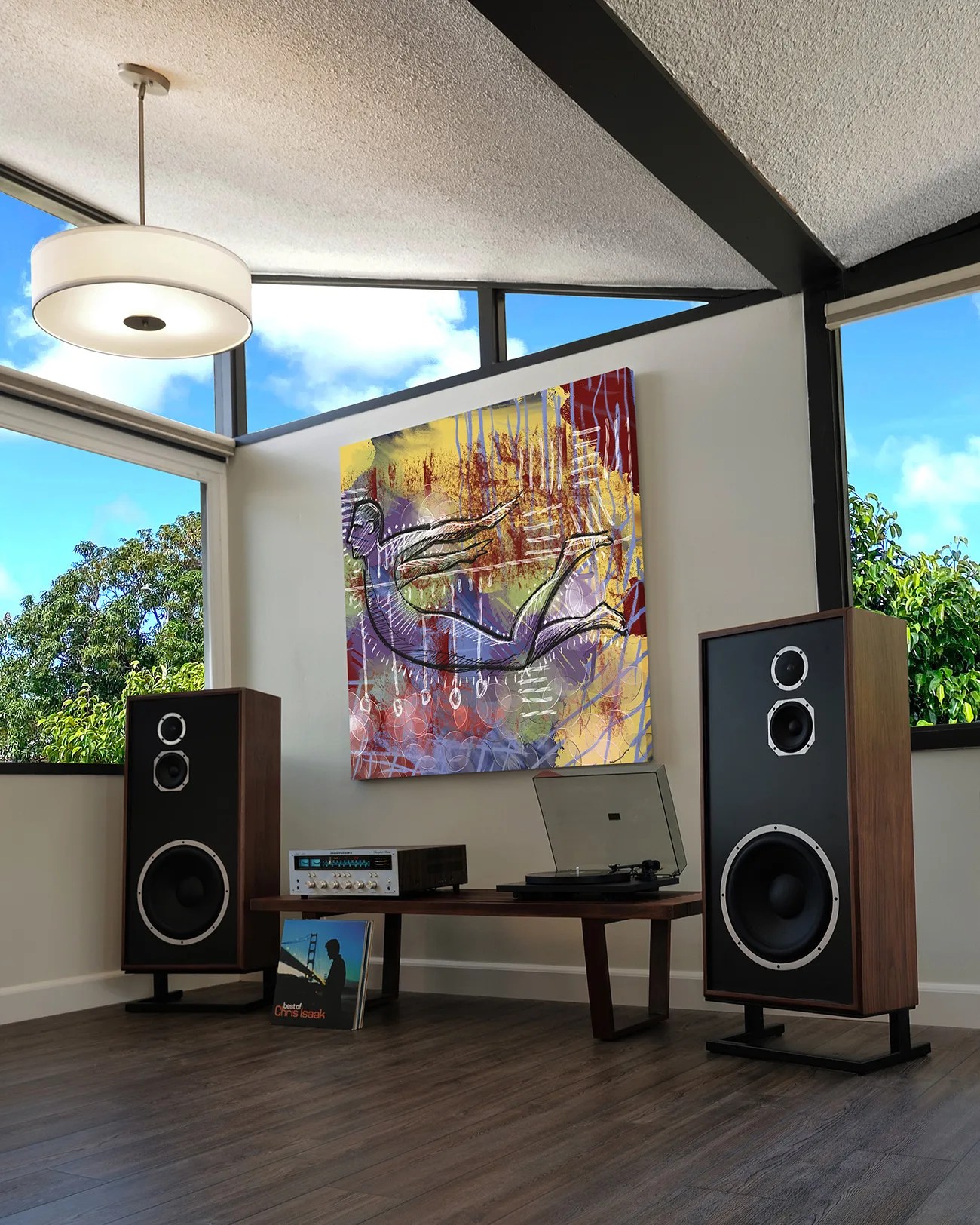 Pair of large vintage wooden floor speakers flanking a low wooden table with stereo receiver and turntable under colorful abstract wall art.