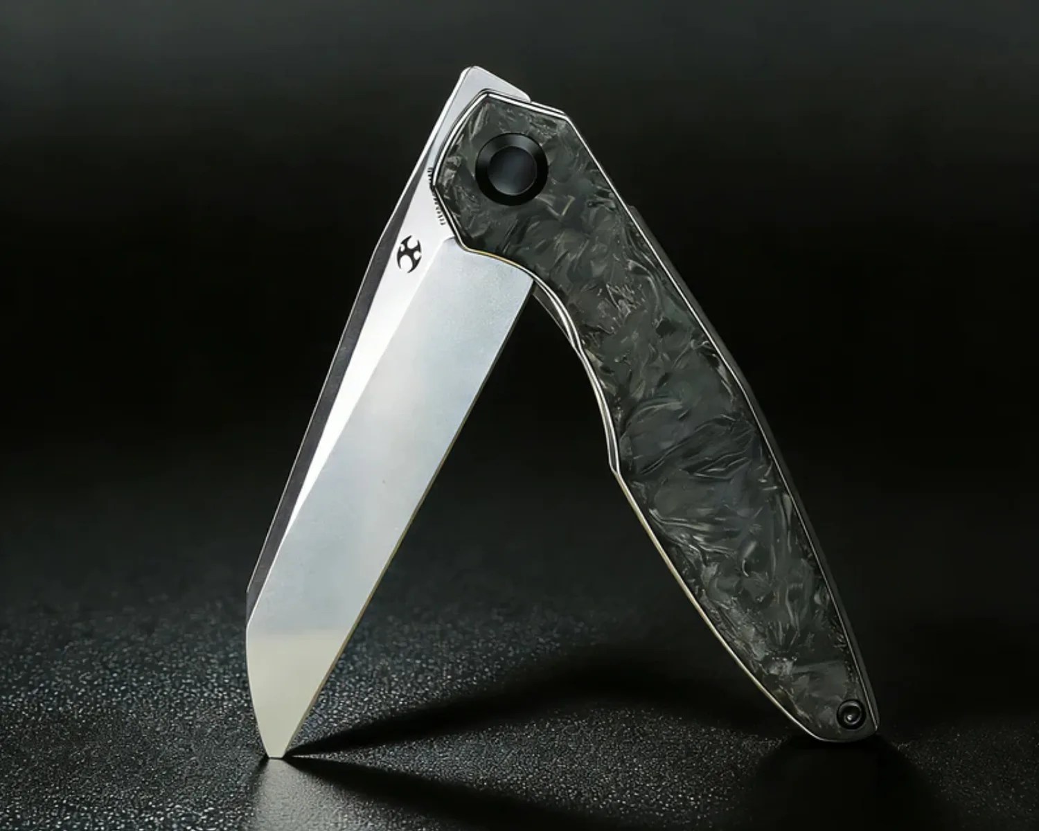 Folding knife with a silver blade and a textured dark gray handle standing open on a black surface.