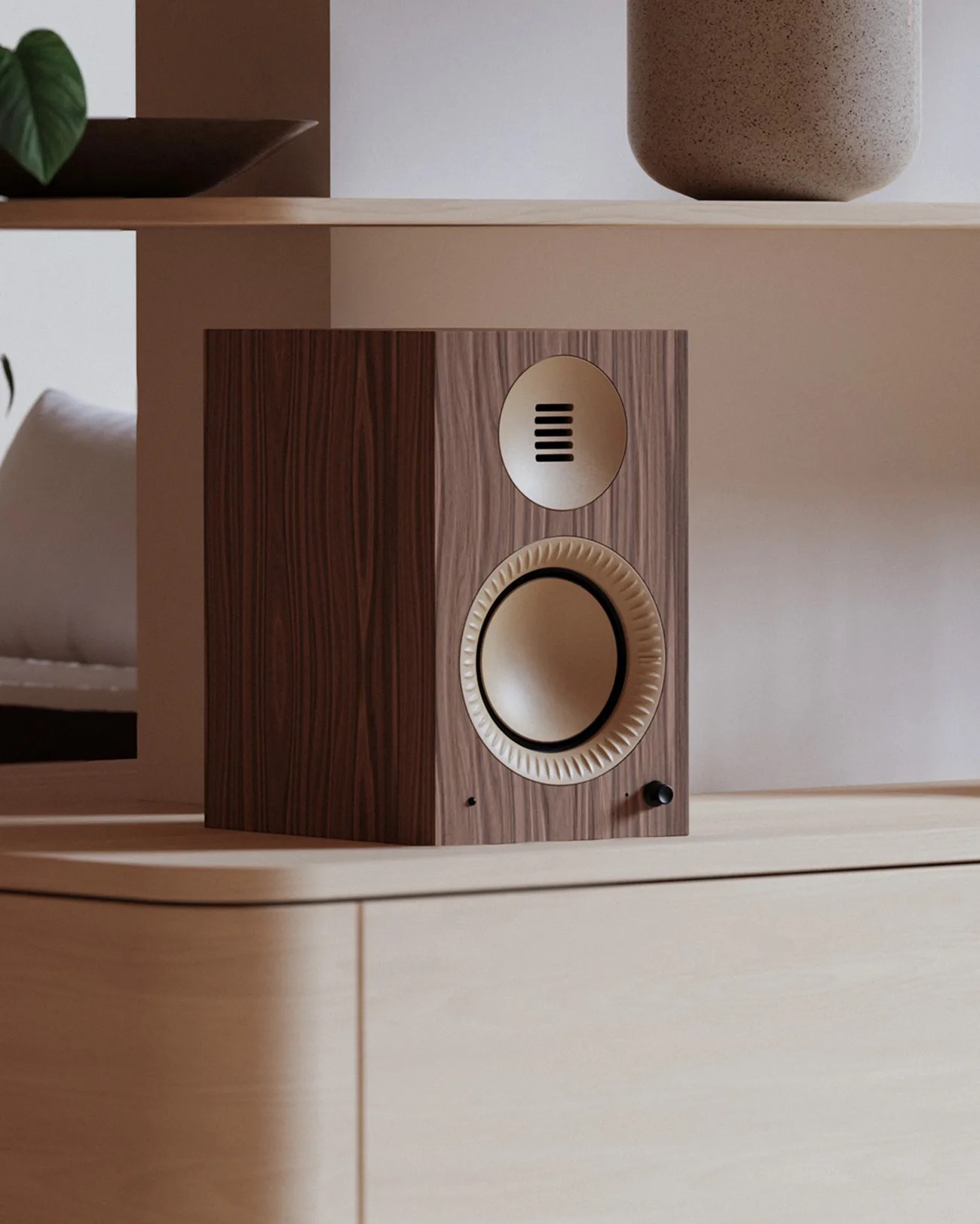 Wooden bookshelf speaker with beige speaker cones and a black volume knob on a light wood cabinet.
