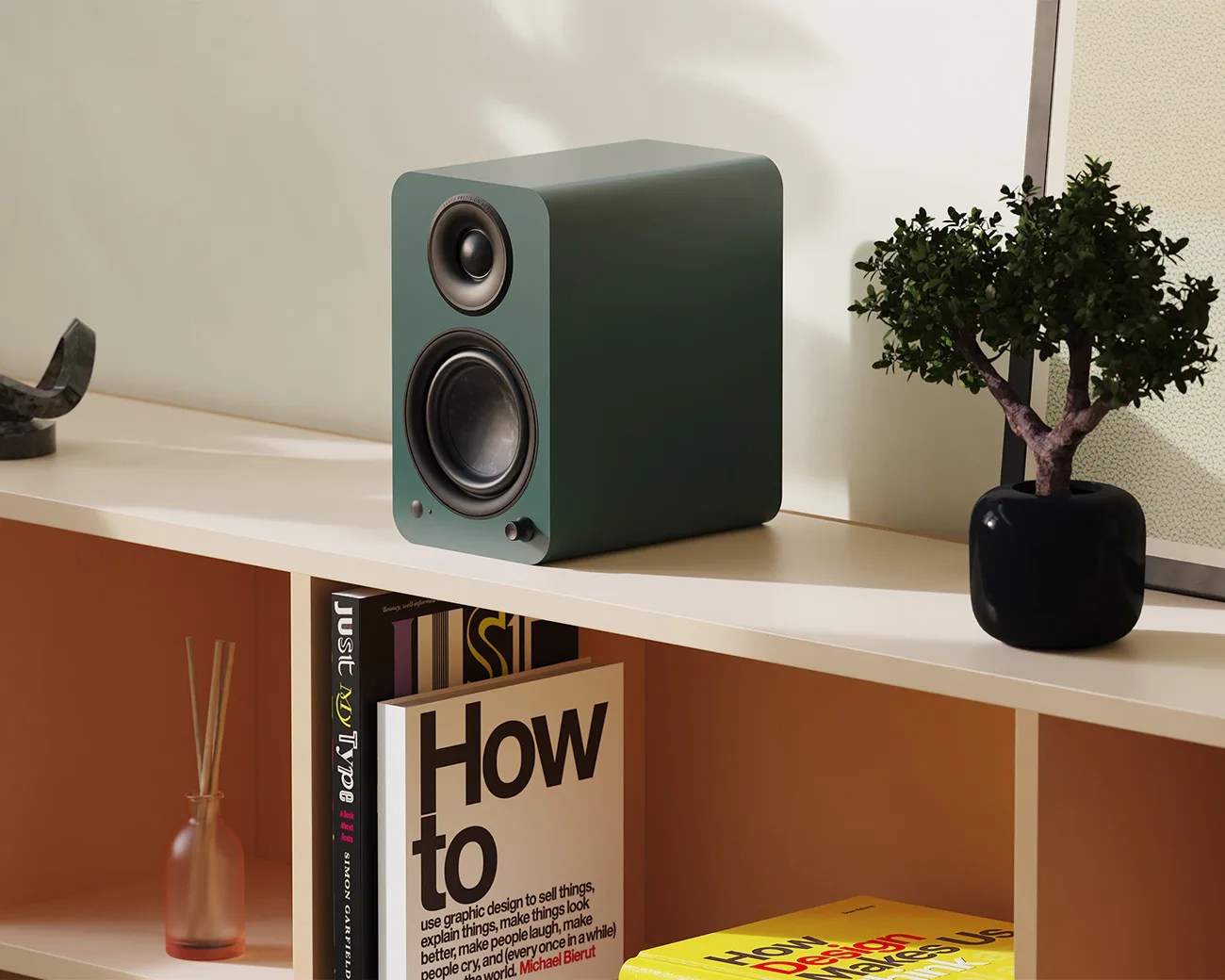 Green rectangular speaker with rounded edges on a white shelf next to a small potted plant and books.