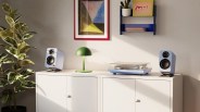 White cabinet with two light blue speakers, a green dome lamp, and a turntable with a clear dust cover on top.