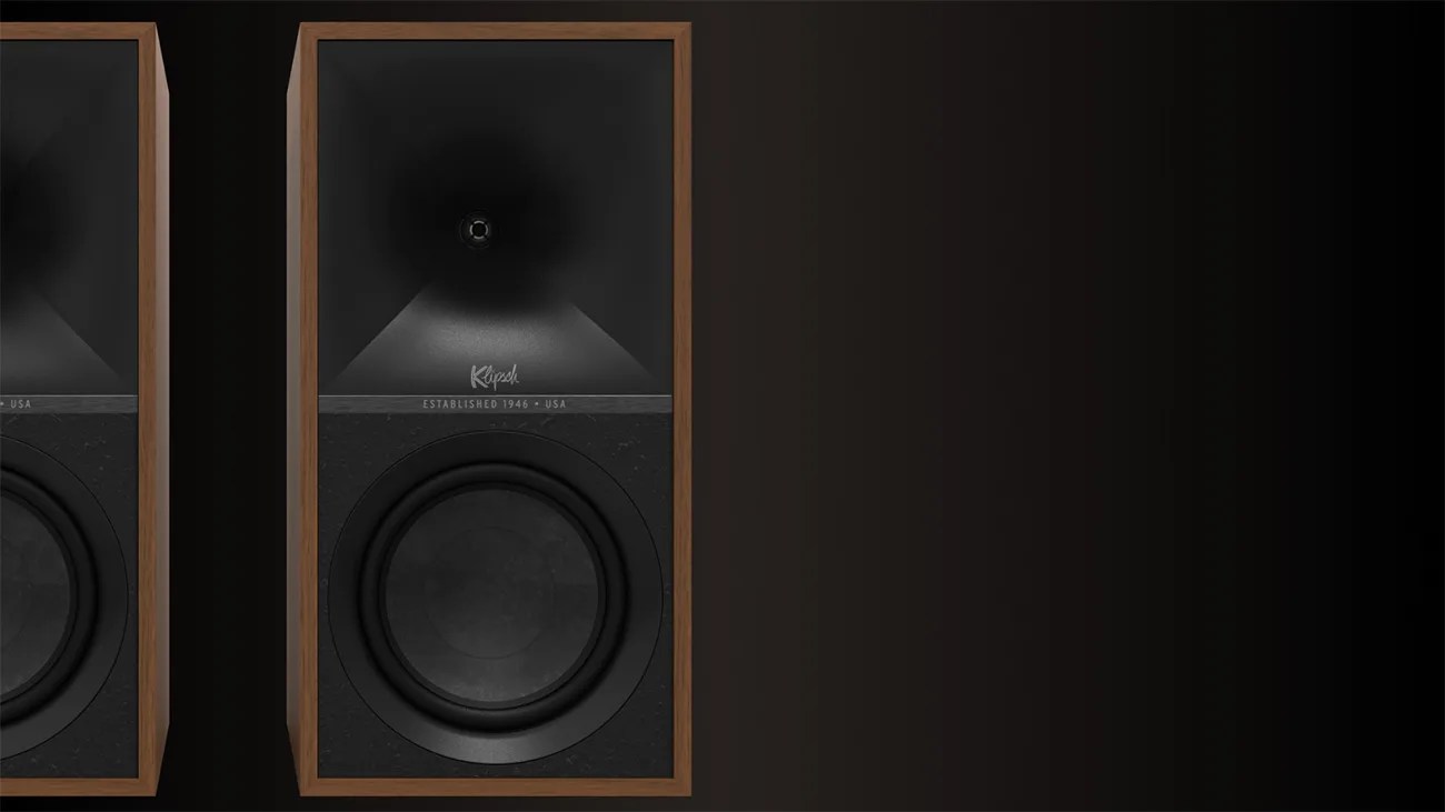 Pair of Klipsch speakers with wooden frames and black front panels on a dark background.