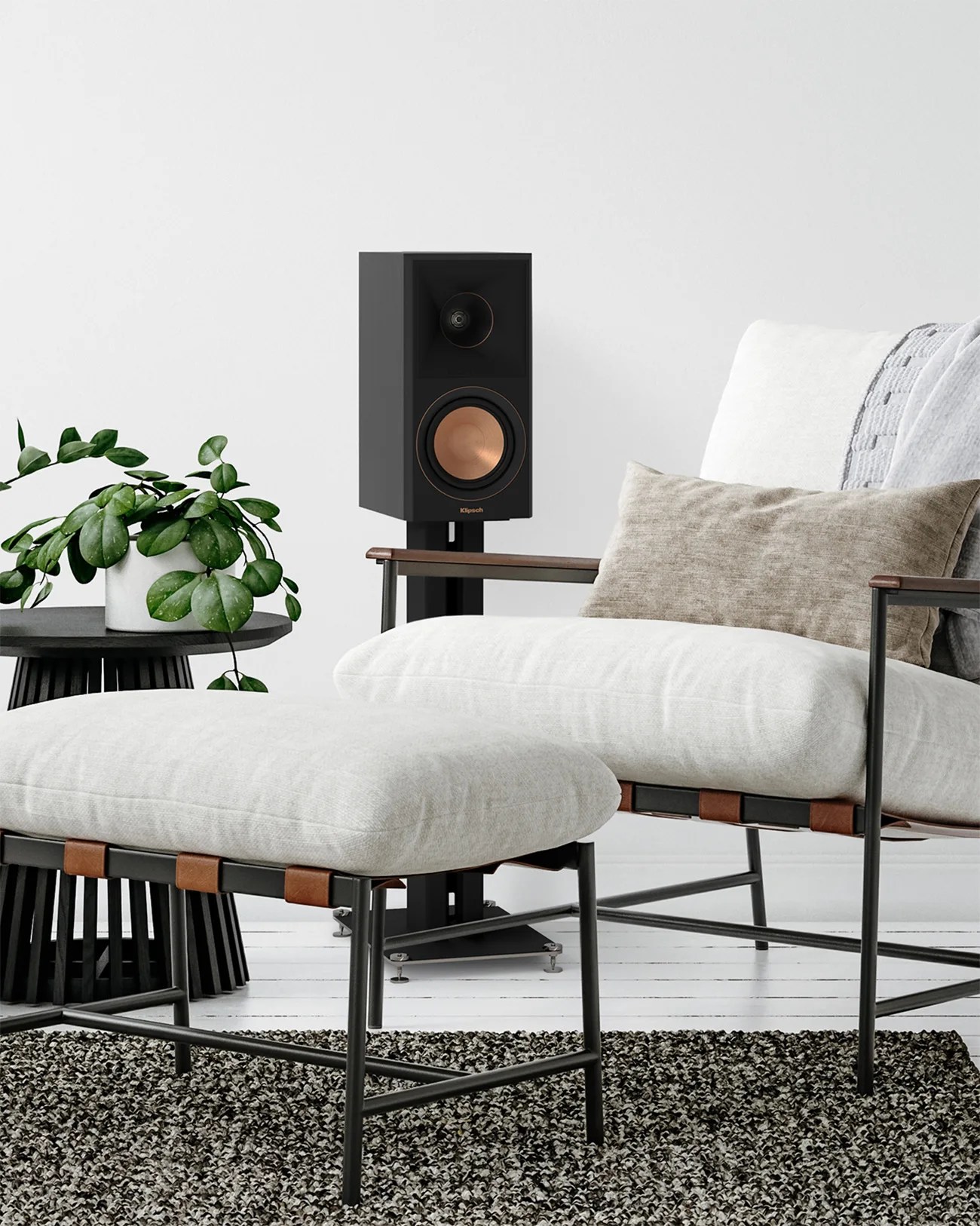 Black Klipsch speaker with copper cone on a black stand next to a white cushioned chair and ottoman.