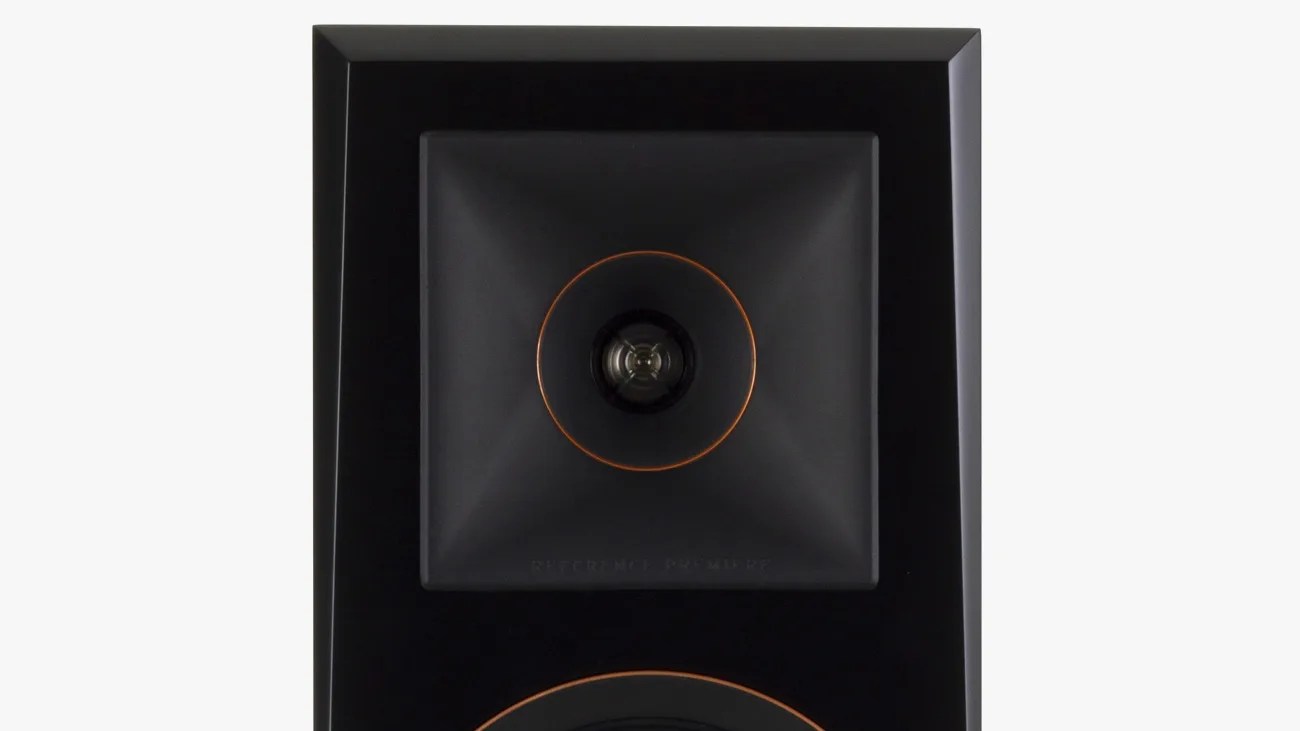Close-up of a black square speaker tweeter with an orange ring around the central dome on a glossy black speaker panel.