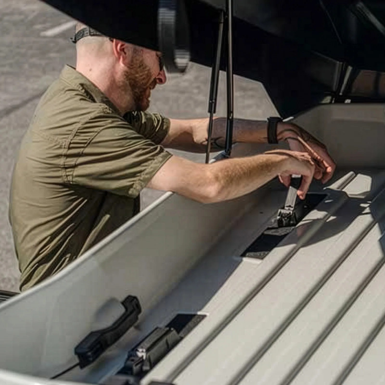 Man in an olive green shirt adjusting black mounting brackets inside a white boat.