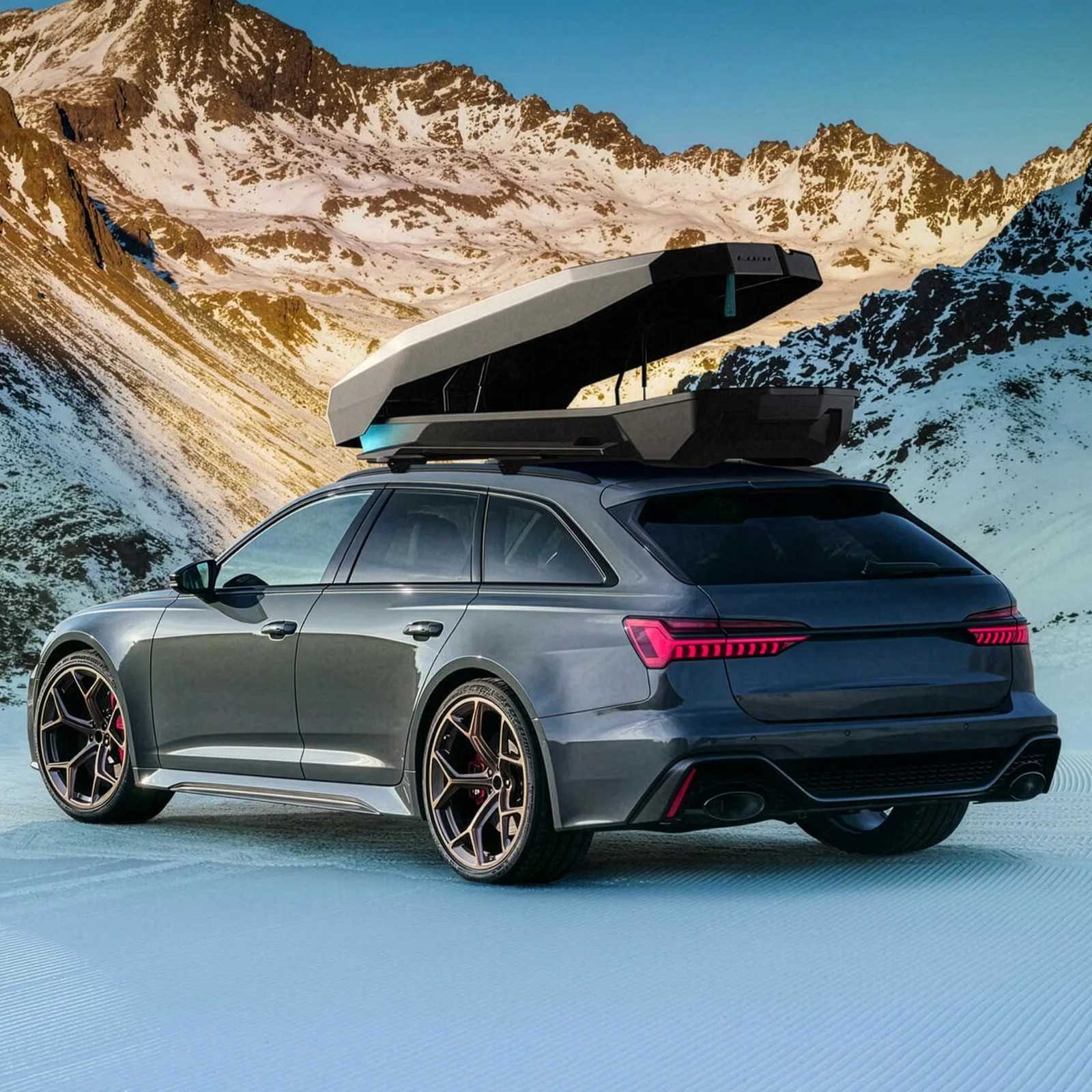 Dark gray station wagon with bronze wheels and an open black and white roof cargo box, parked on snow with mountains in the background.
