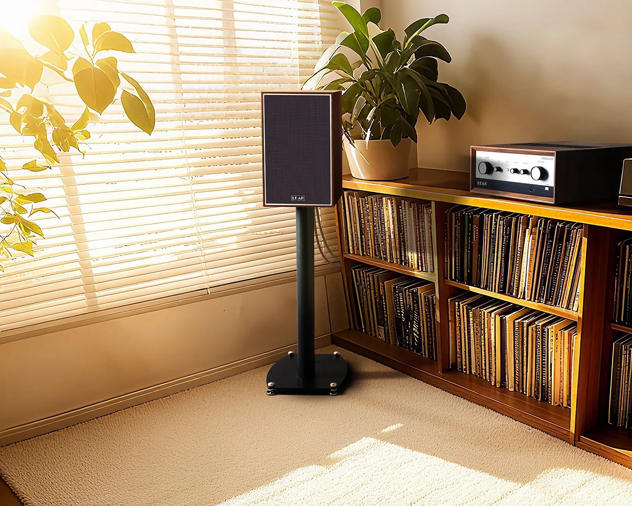 Black LEAK speaker on a black stand next to a wooden shelf filled with vinyl records and a LEAK amplifier.