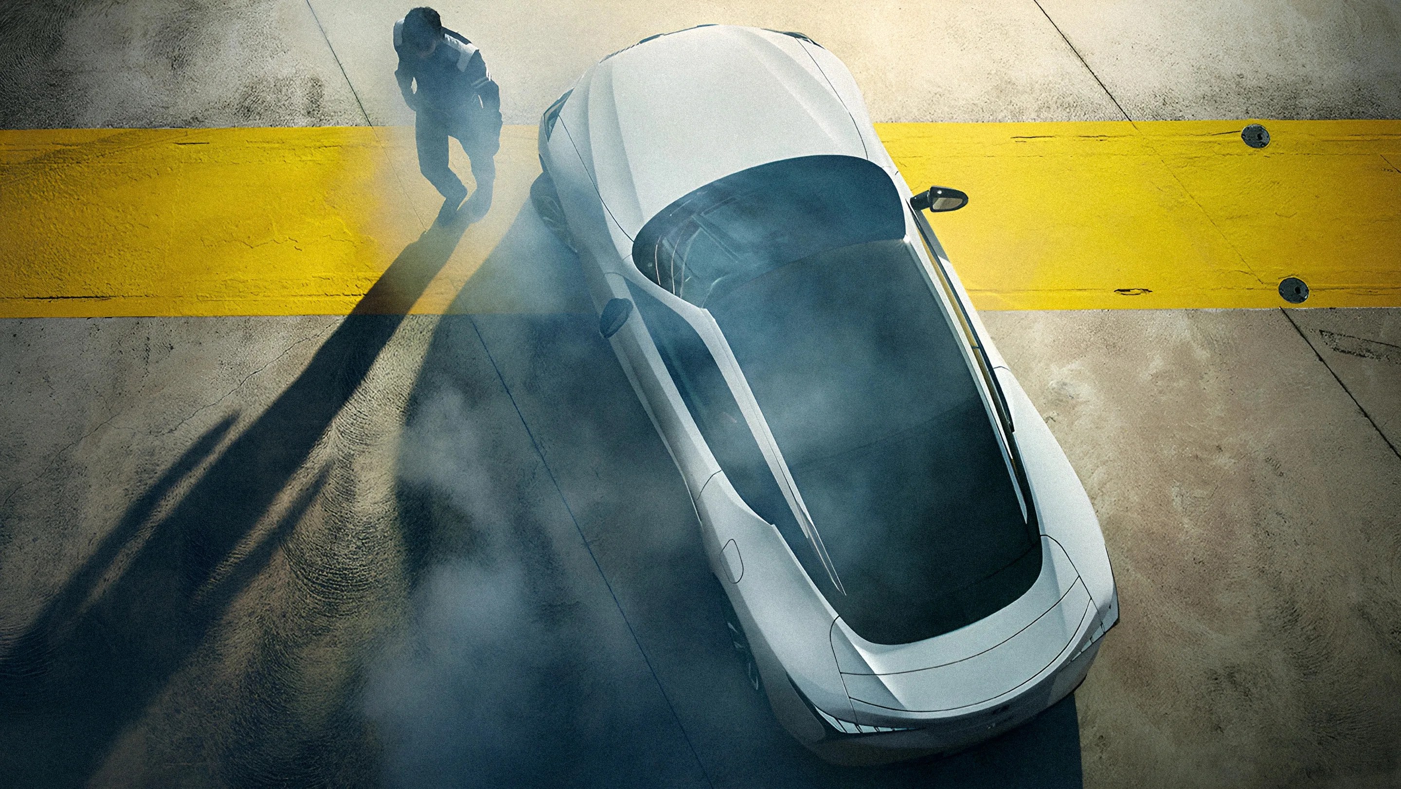 White sports car with tinted windows on concrete near a wide yellow line, with smoke and a person standing nearby.