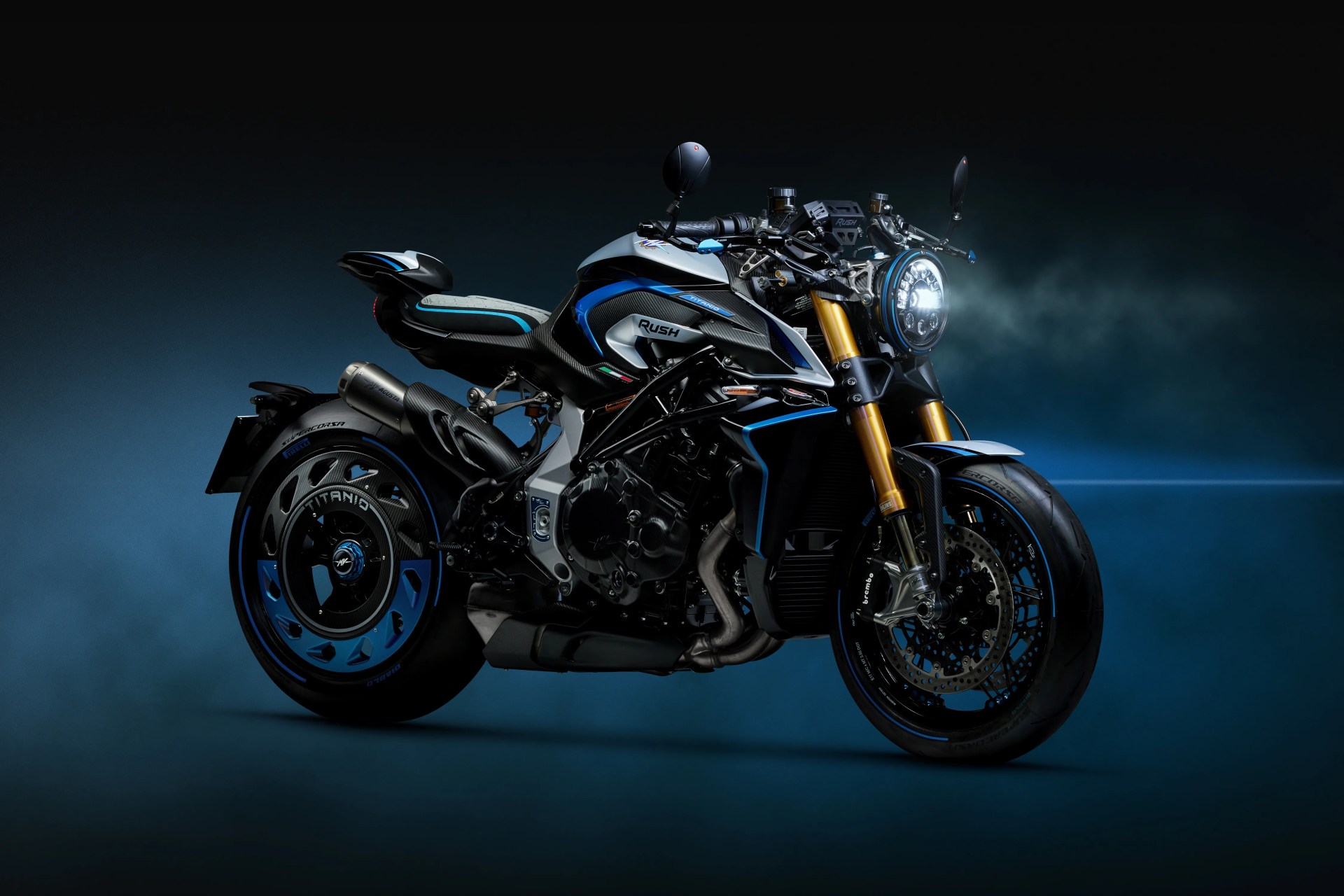 Black and blue MV Agusta Rush motorcycle with gold front forks and illuminated headlight on a dark blue background.