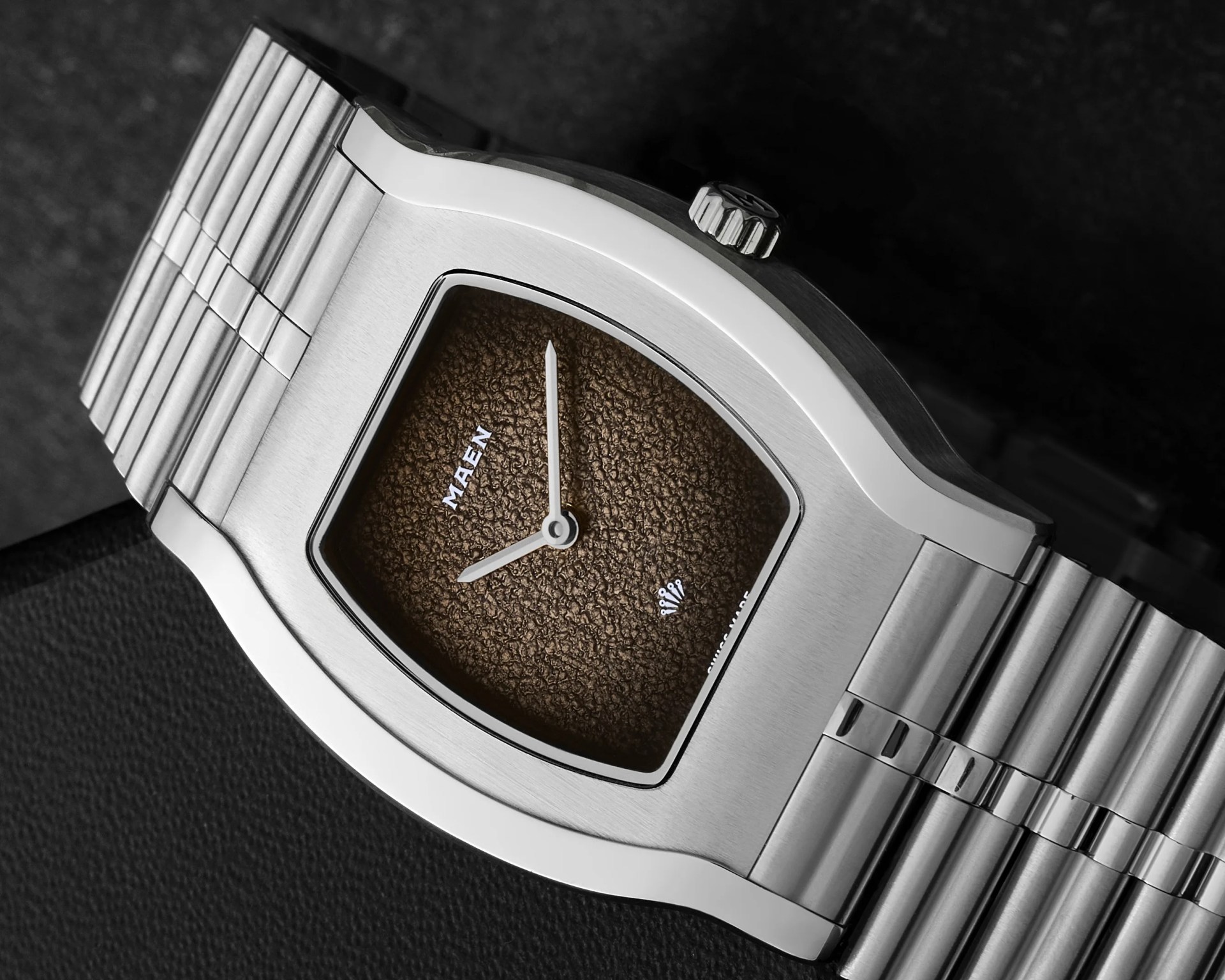 Silver stainless steel wristwatch with a textured brown dial and minimalist hands.