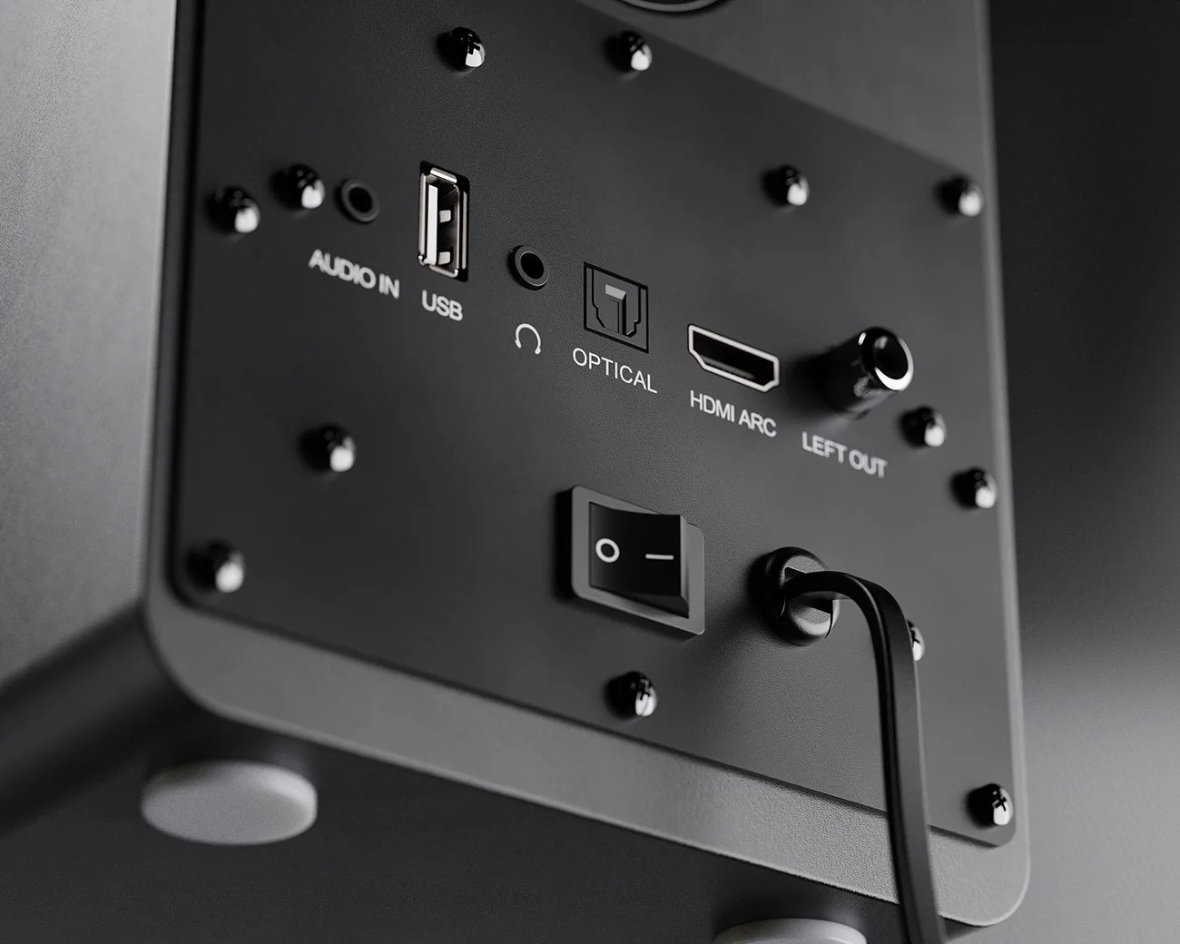 Close-up of black speaker back panel showing audio in, USB, optical, HDMI ARC, left out ports, power switch, and connected power cable.