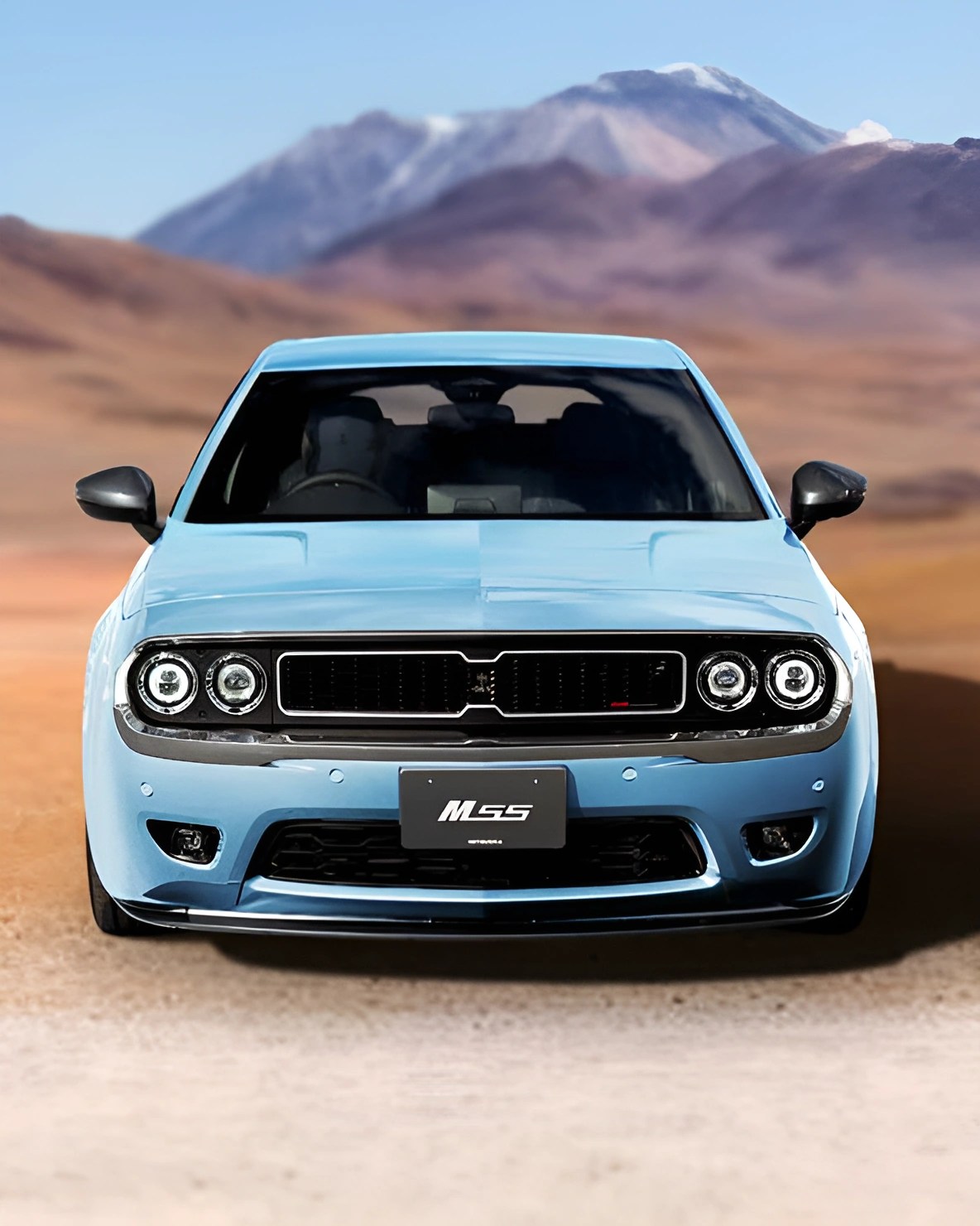Light blue muscle car with black grille and round headlights parked on a desert road with mountains in the background.