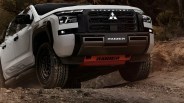 White Mitsubishi Raider pickup truck with black grille and off-road tires on a dirt trail.