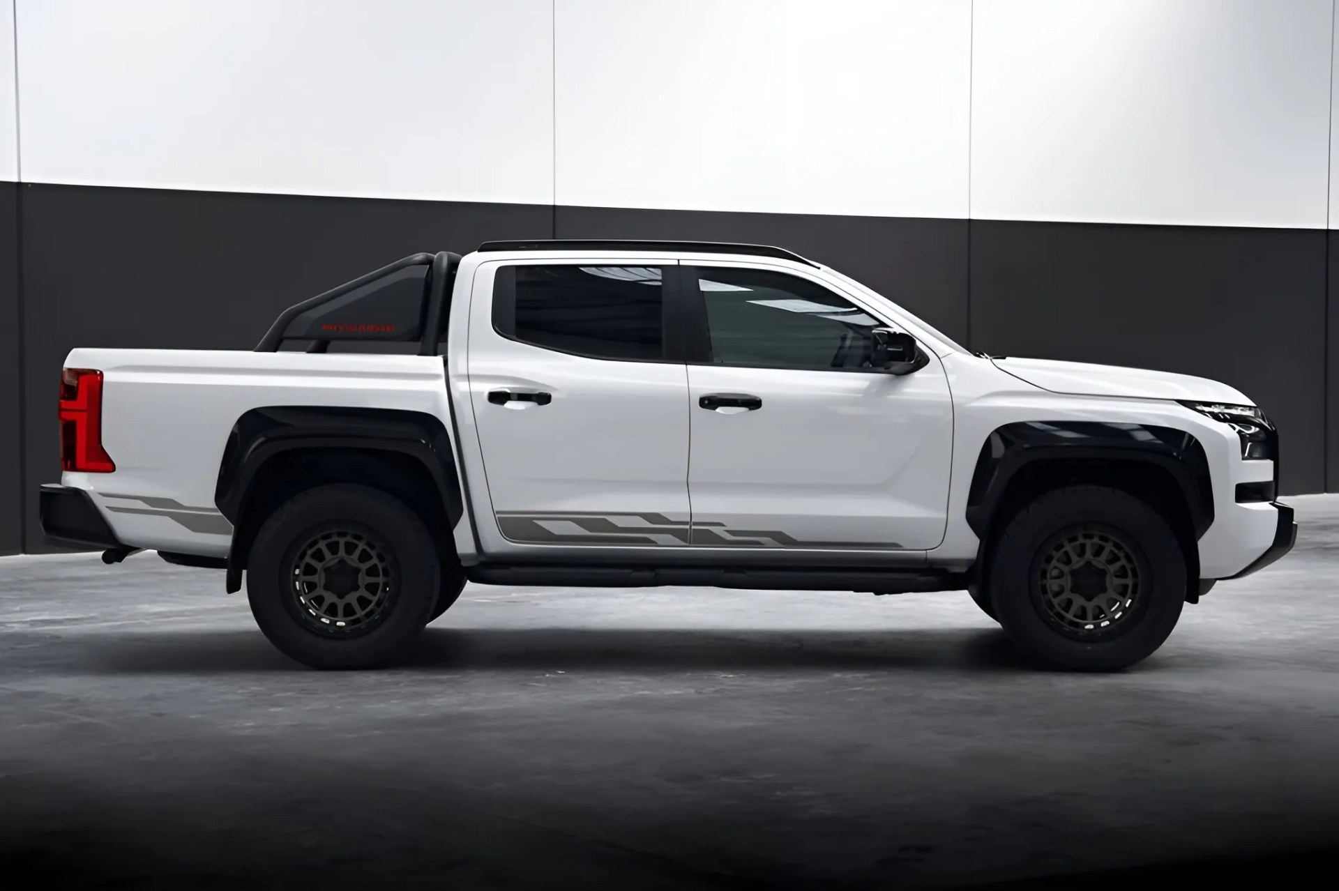White four-door pickup truck with black fender flares and off-road tires in a studio setting.