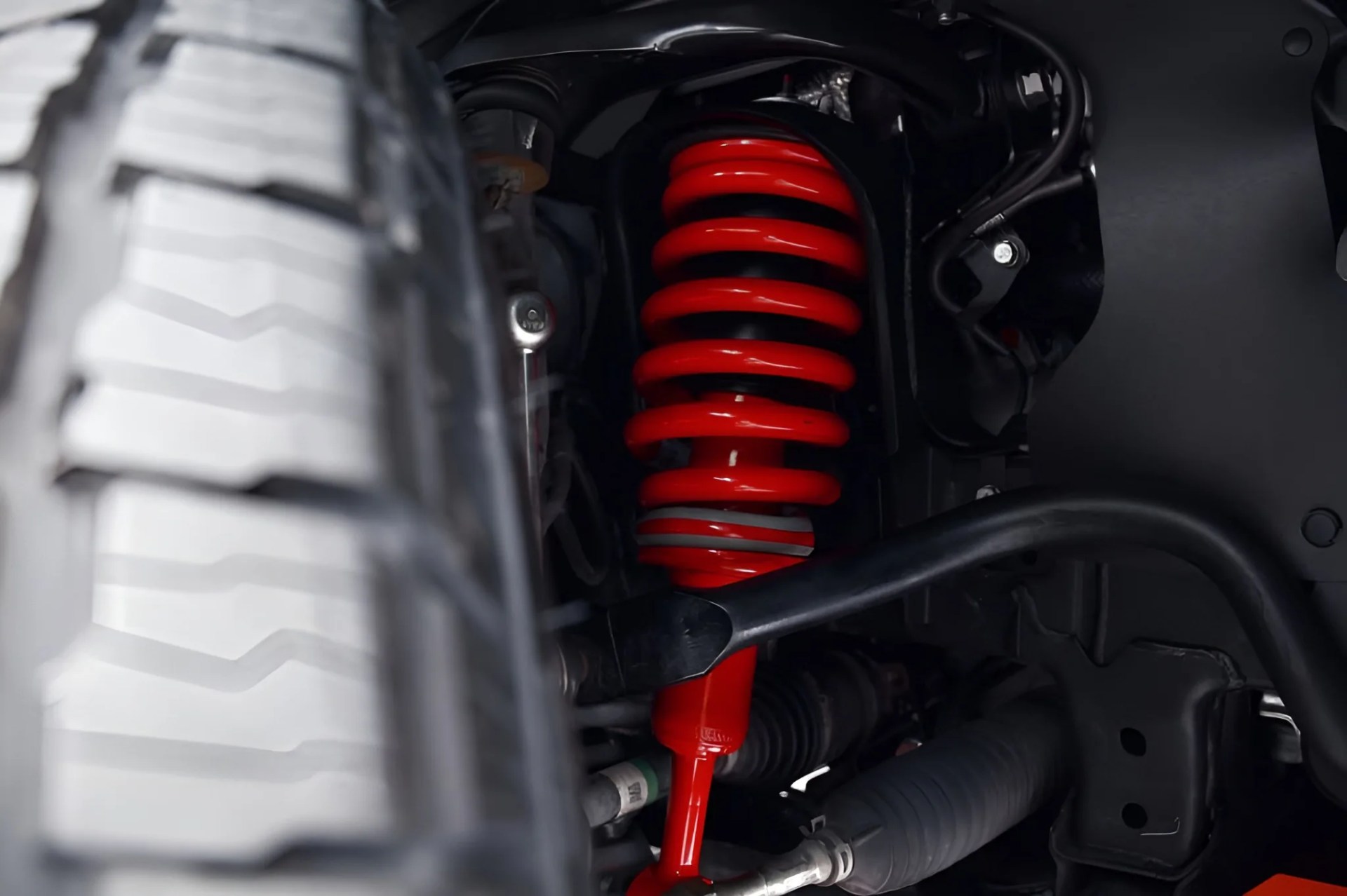 Red coil spring suspension system visible behind a vehicle tire.