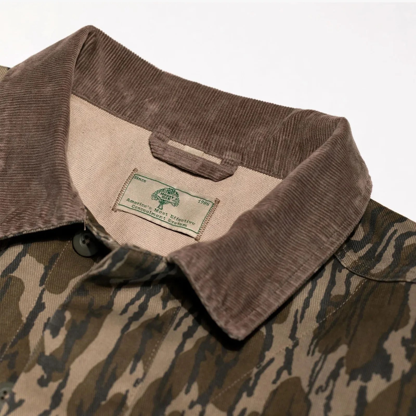 Brown corduroy collar on a camouflage-patterned jacket with a beige inner lining and a green label.