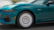 Front side of a teal car with a spinning white wheel and "5.0" badge on the fender.