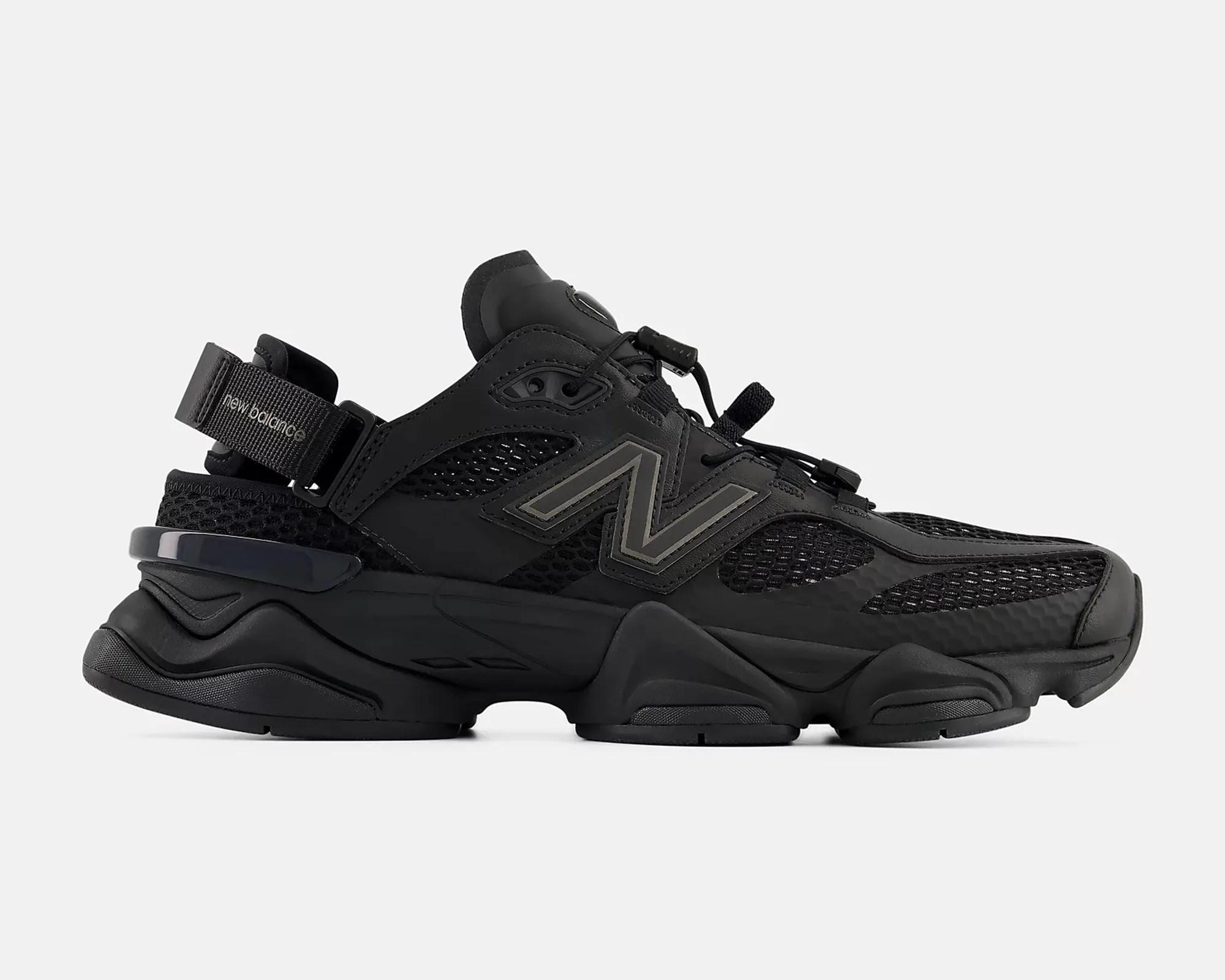 Black New Balance sneaker with mesh panels, thick sole, and adjustable strap on the heel.