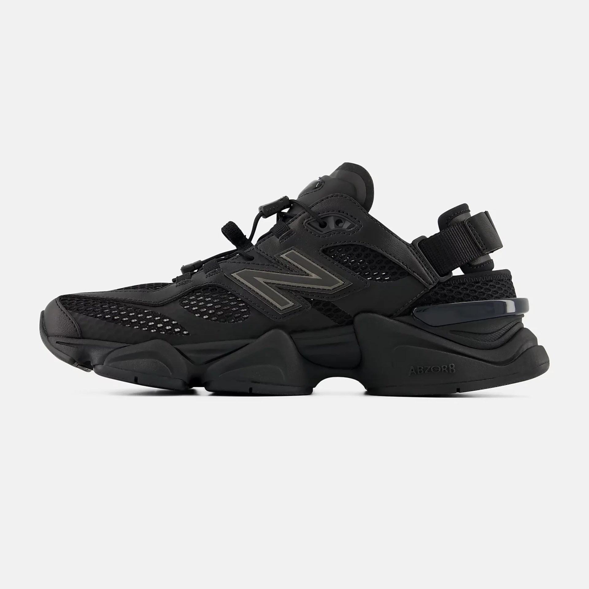 Black New Balance sneaker with mesh panels, thick sole, and adjustable strap at the heel.