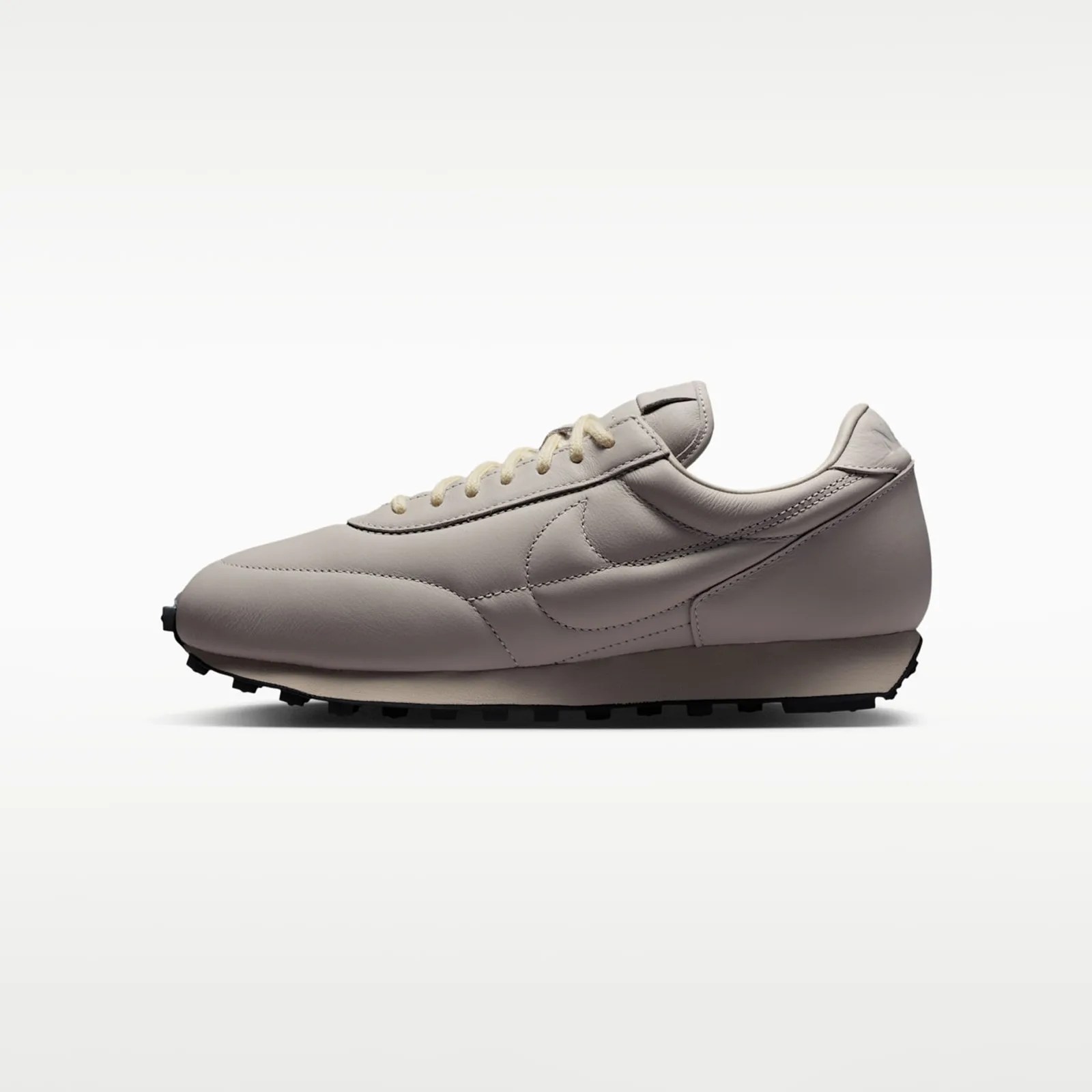 Light beige leather Nike sneaker with cream laces and black rubber sole, side view.