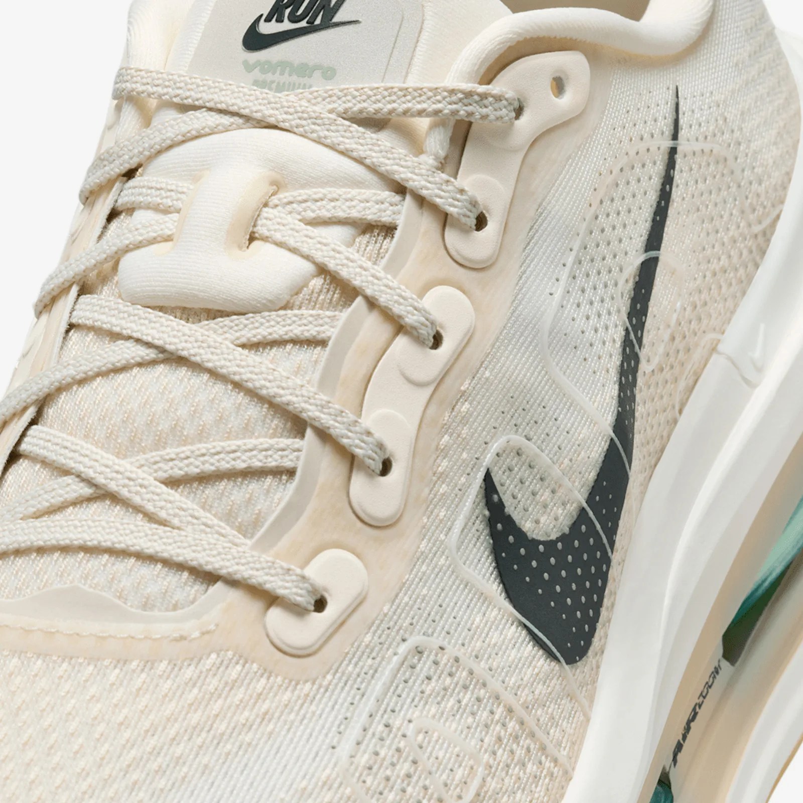 Close-up of a beige Nike running shoe with textured fabric, beige laces, and a black Nike swoosh logo.