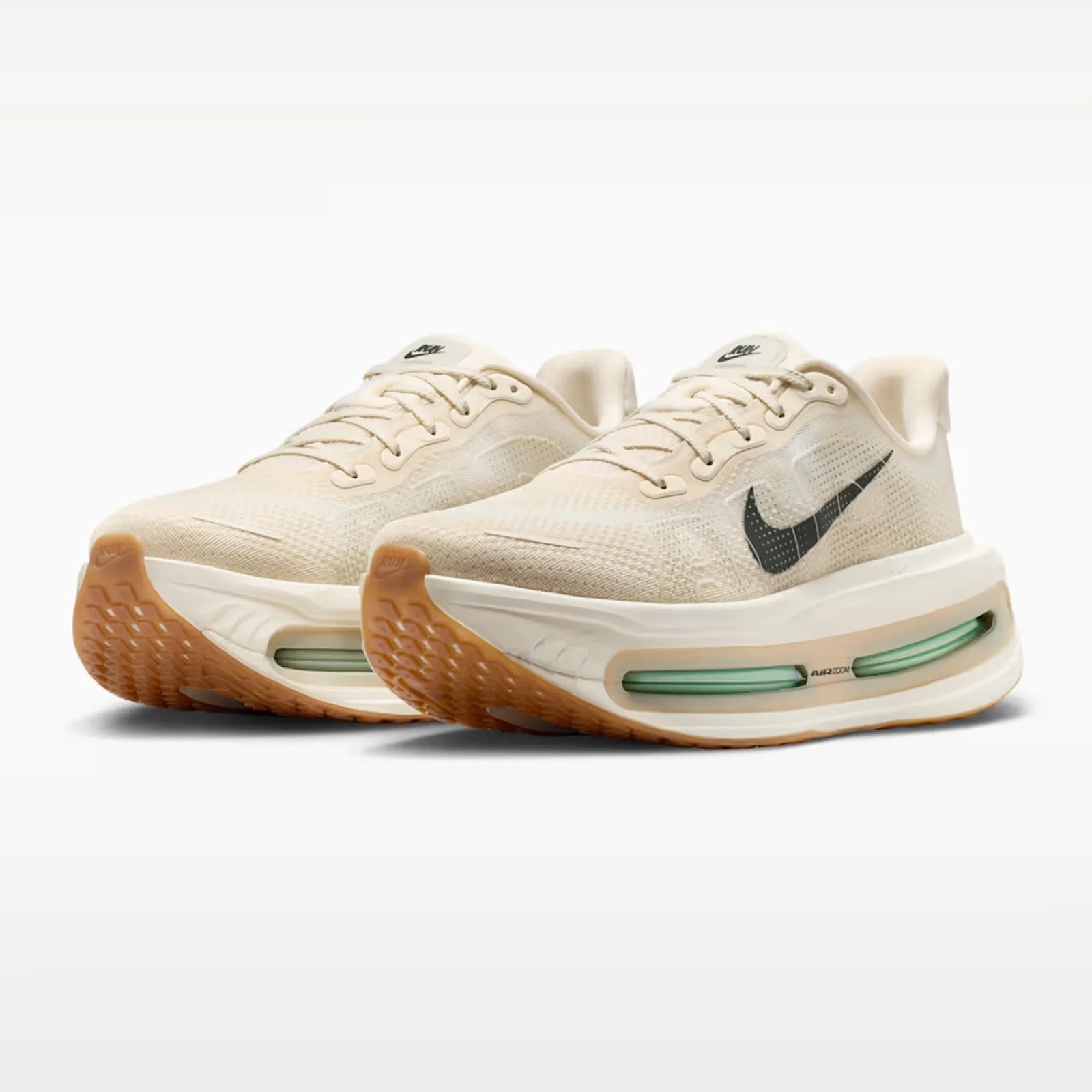 Pair of beige Nike Air Zoom running shoes with black swoosh logos and gum rubber soles.