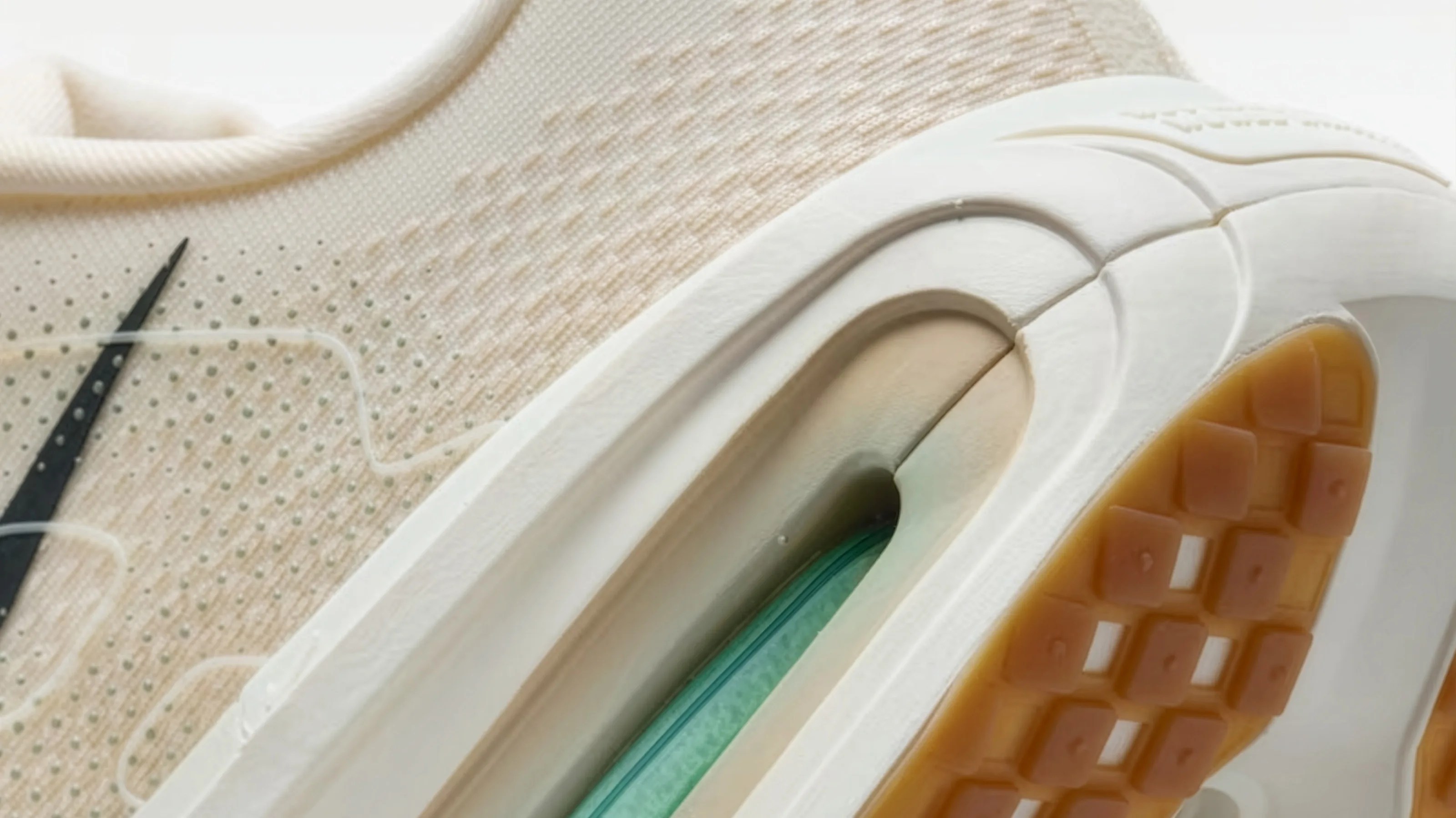 Close-up of a beige Nike sneaker showing the textured fabric upper, black swoosh, and white sole with visible air cushioning and gum rubber tread.