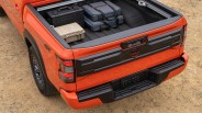 Orange Nissan Frontier Pro-4X truck bed with black and beige hard cases and gray soft cases inside.