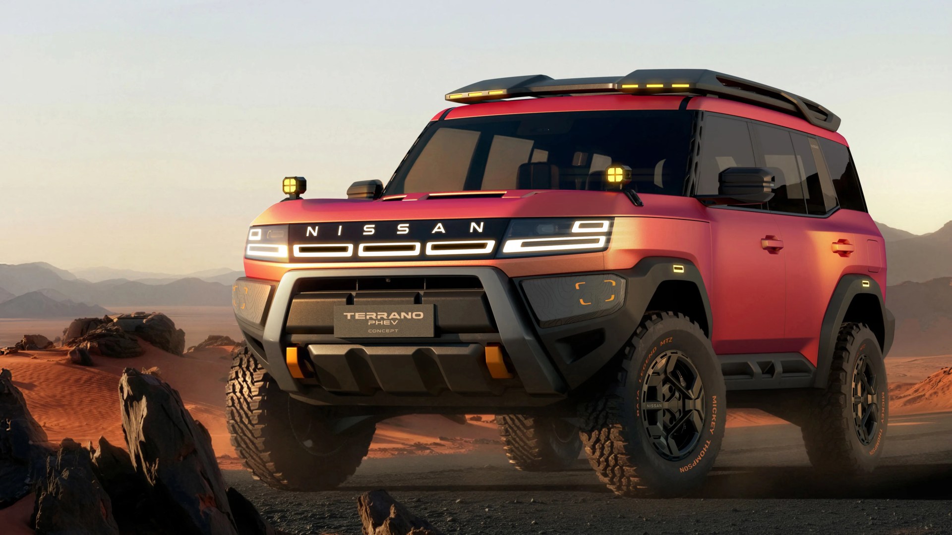 Red Nissan Terrano PHEV concept SUV with off-road tires and roof rack on rocky desert terrain at sunset.