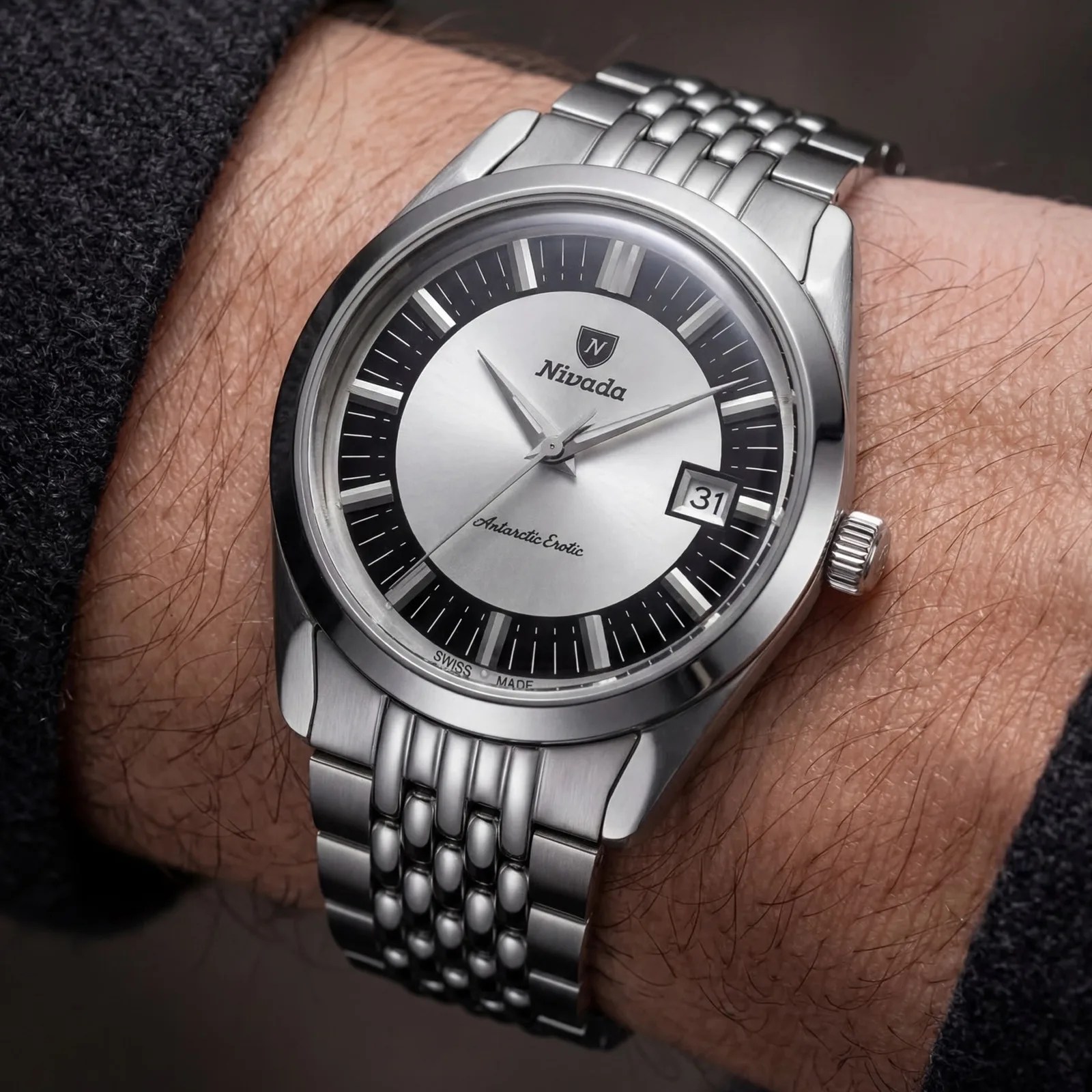 Silver Nivada Antarctic Exotic wristwatch with black and silver dial and date window on a metal bracelet worn on a wrist.