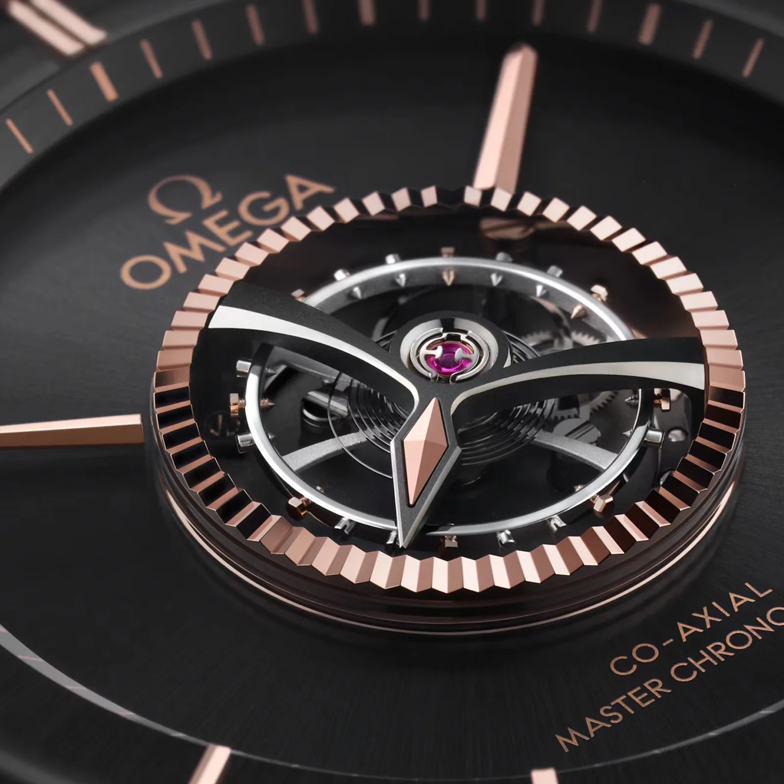 Close-up of an Omega watch dial showing the Co-Axial Master Chronometer mechanism with rose gold and black details.