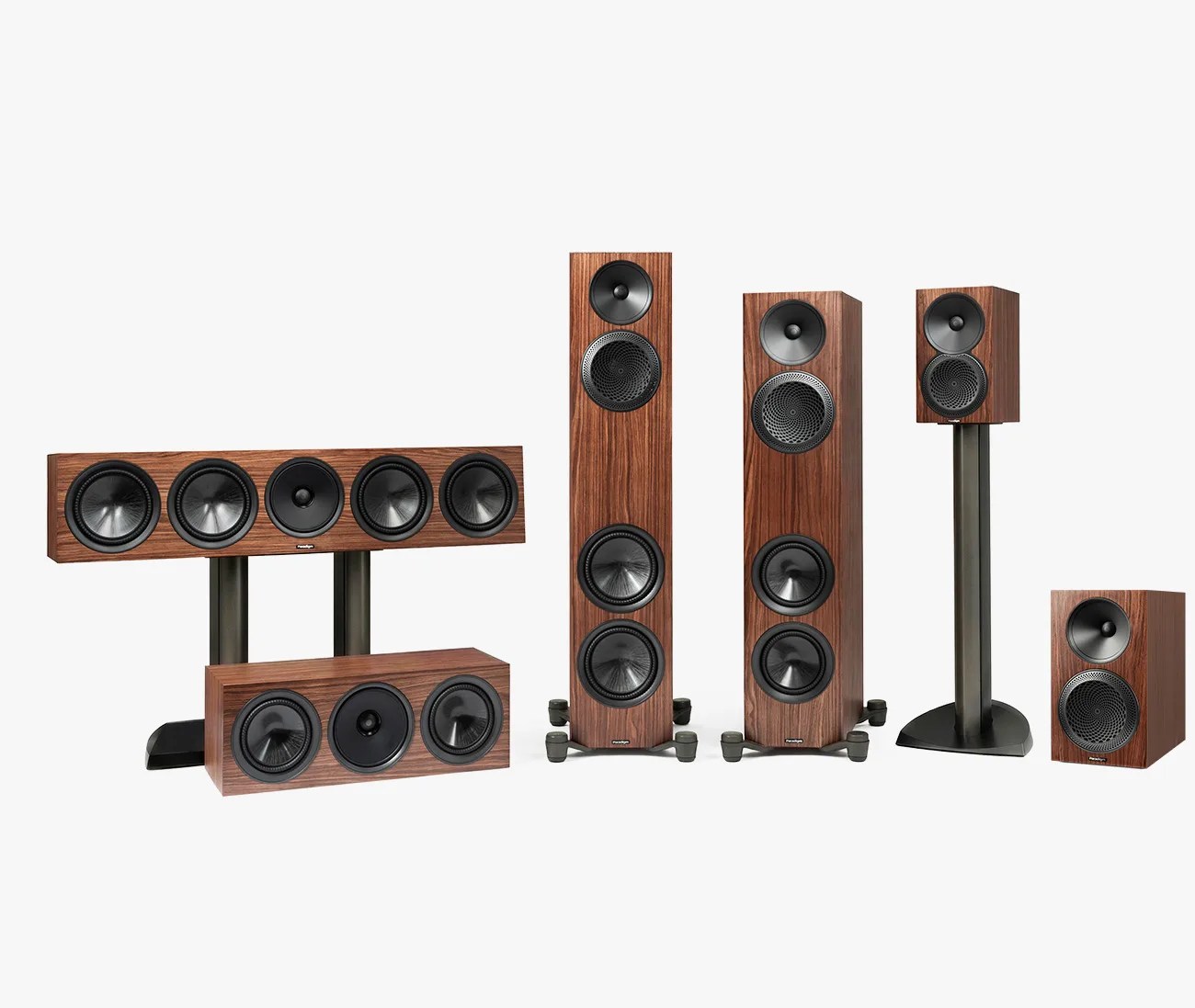 Set of five wooden speakers with black drivers, including two tall floor-standing, one center channel, one bookshelf on a stand, and one bookshelf speaker.