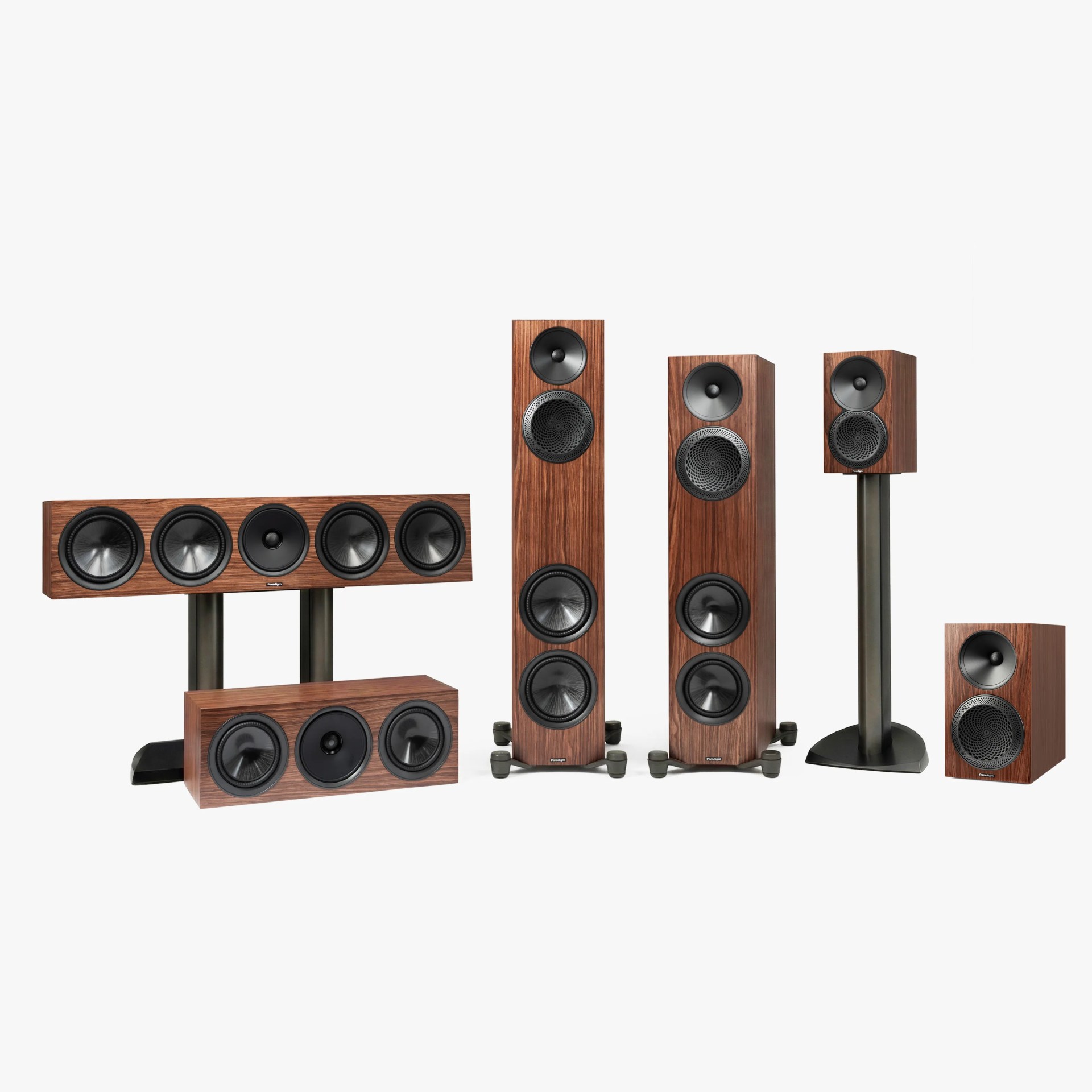 Set of six wooden speakers including two tall floor-standing, two horizontal center channel, one bookshelf on a stand, and one bookshelf speaker.