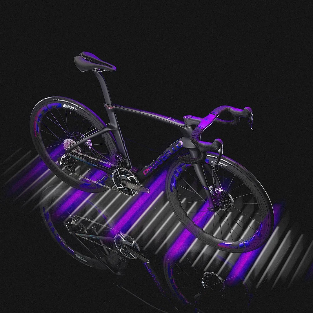 Matte black Pinarello road bike with drop handlebars and Zipp wheels under purple and white lighting.